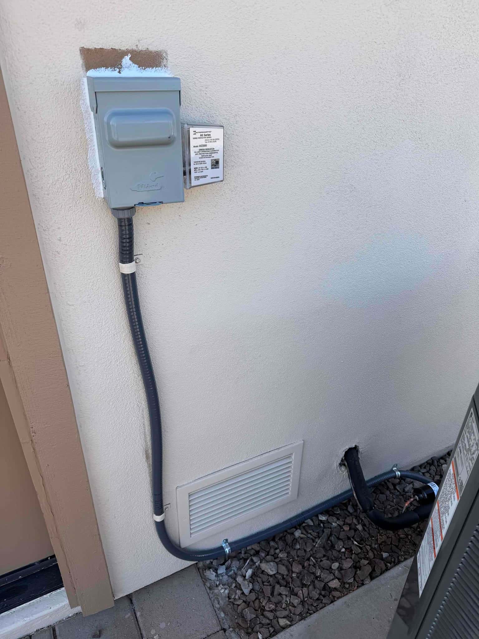 Outdoor AC disconnect and liquidtight conduit neatly routed to the condenser with sealed wall penetrations and secured straps.