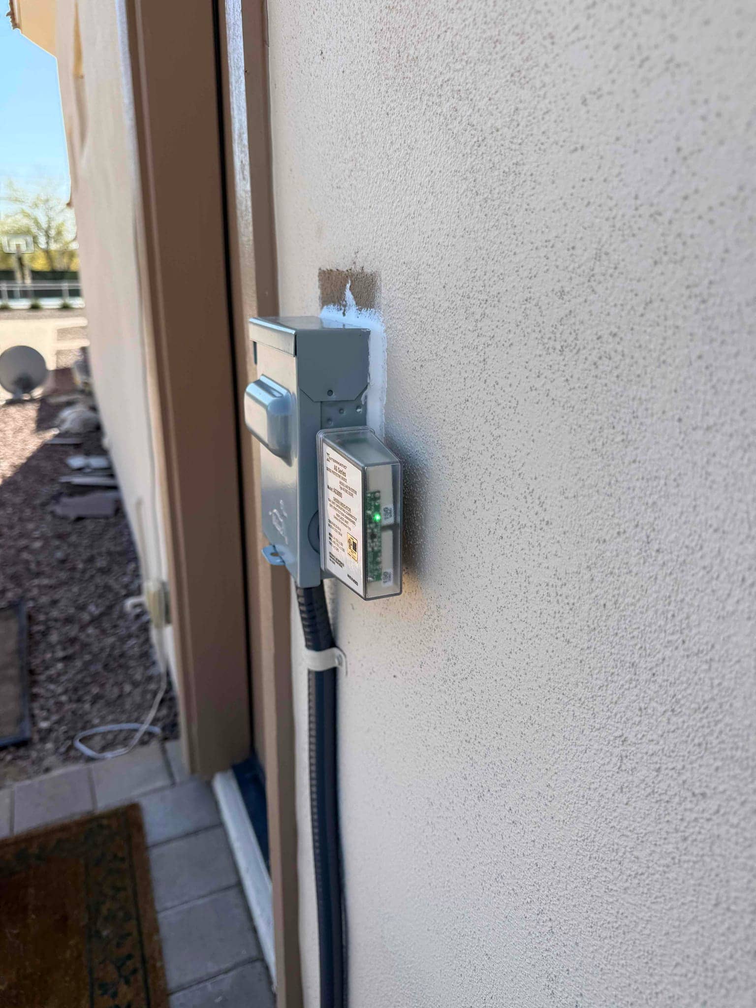 Outdoor HVAC disconnect with sealed wall penetration and flexible conduit mounted neatly along the exterior wall.