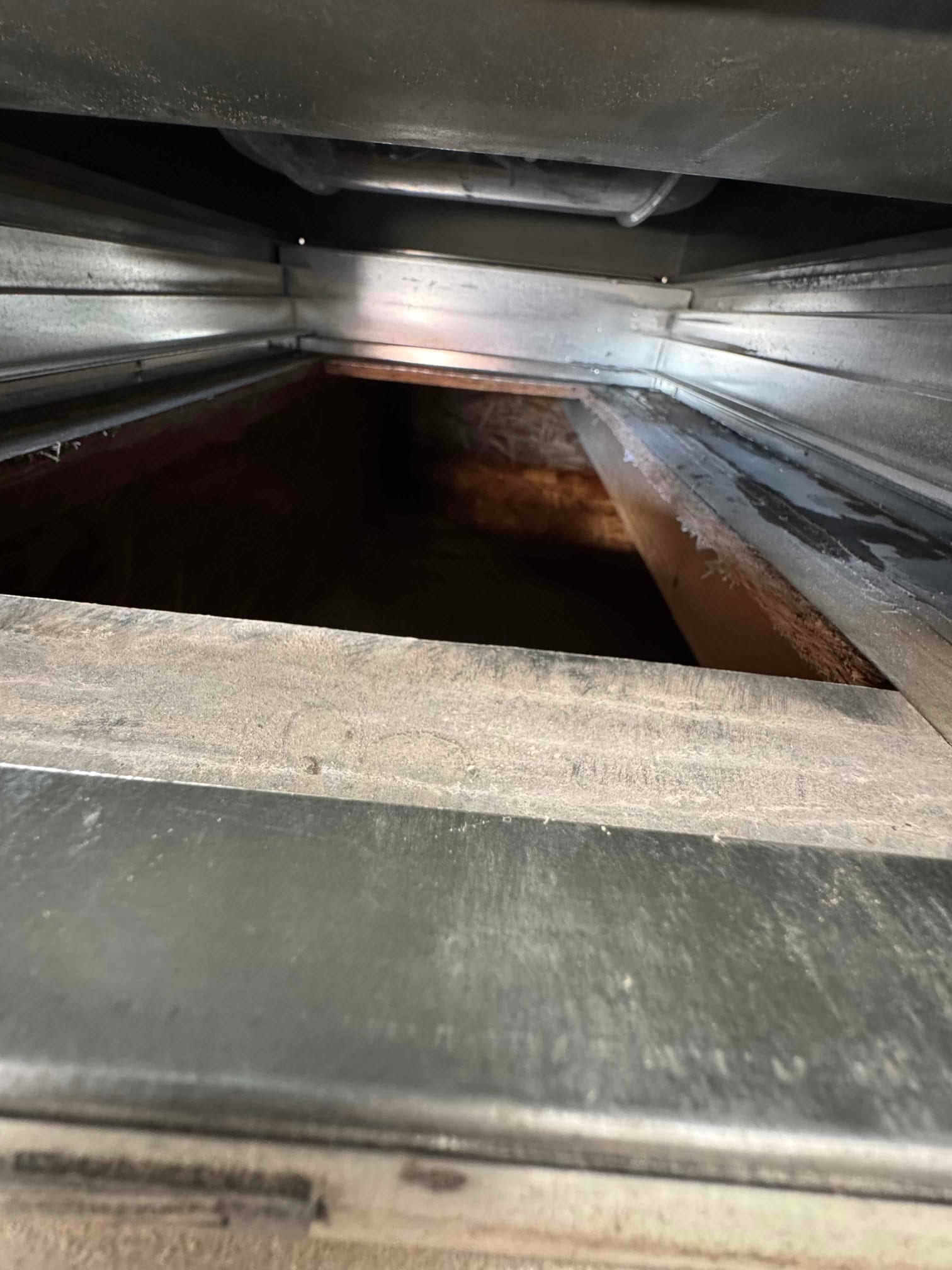 Return air duct interior with accumulated dust on galvanized surfaces, showing the airflow path toward the air handler.