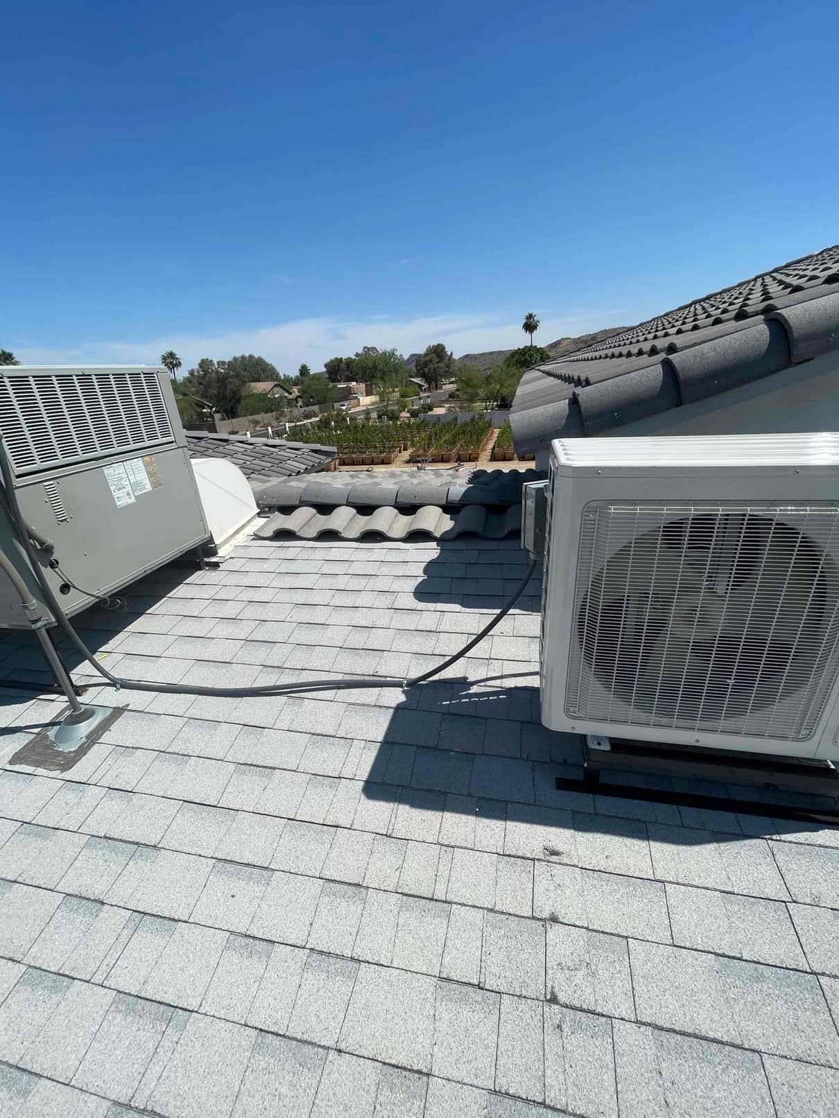 Rooftop installation showing a mini-split outdoor unit on mounting rails with insulated line set routed to the system.