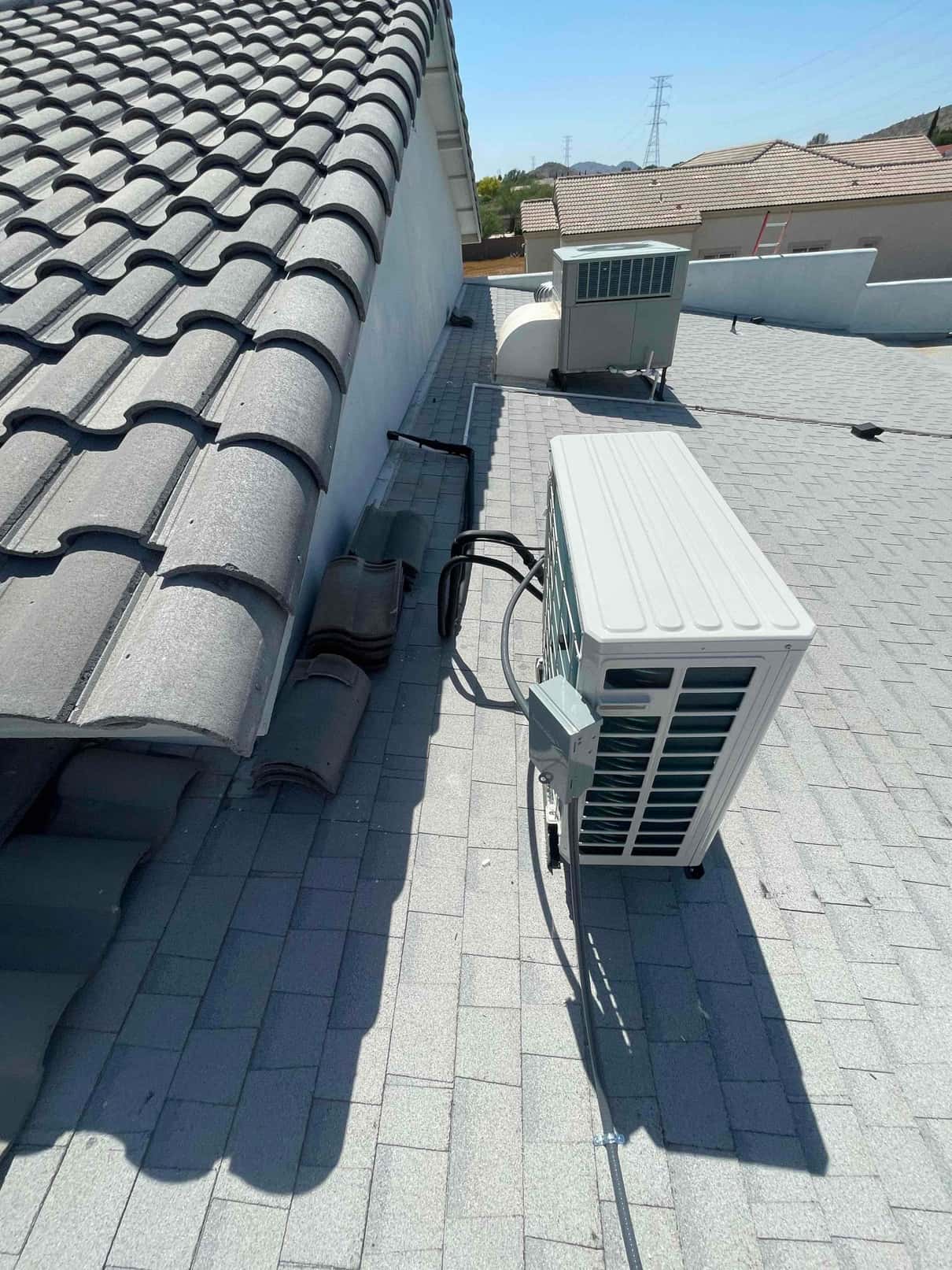 Rooftop mini-split condenser set on shingles with sealed line set penetration and mounted electrical disconnect in place.