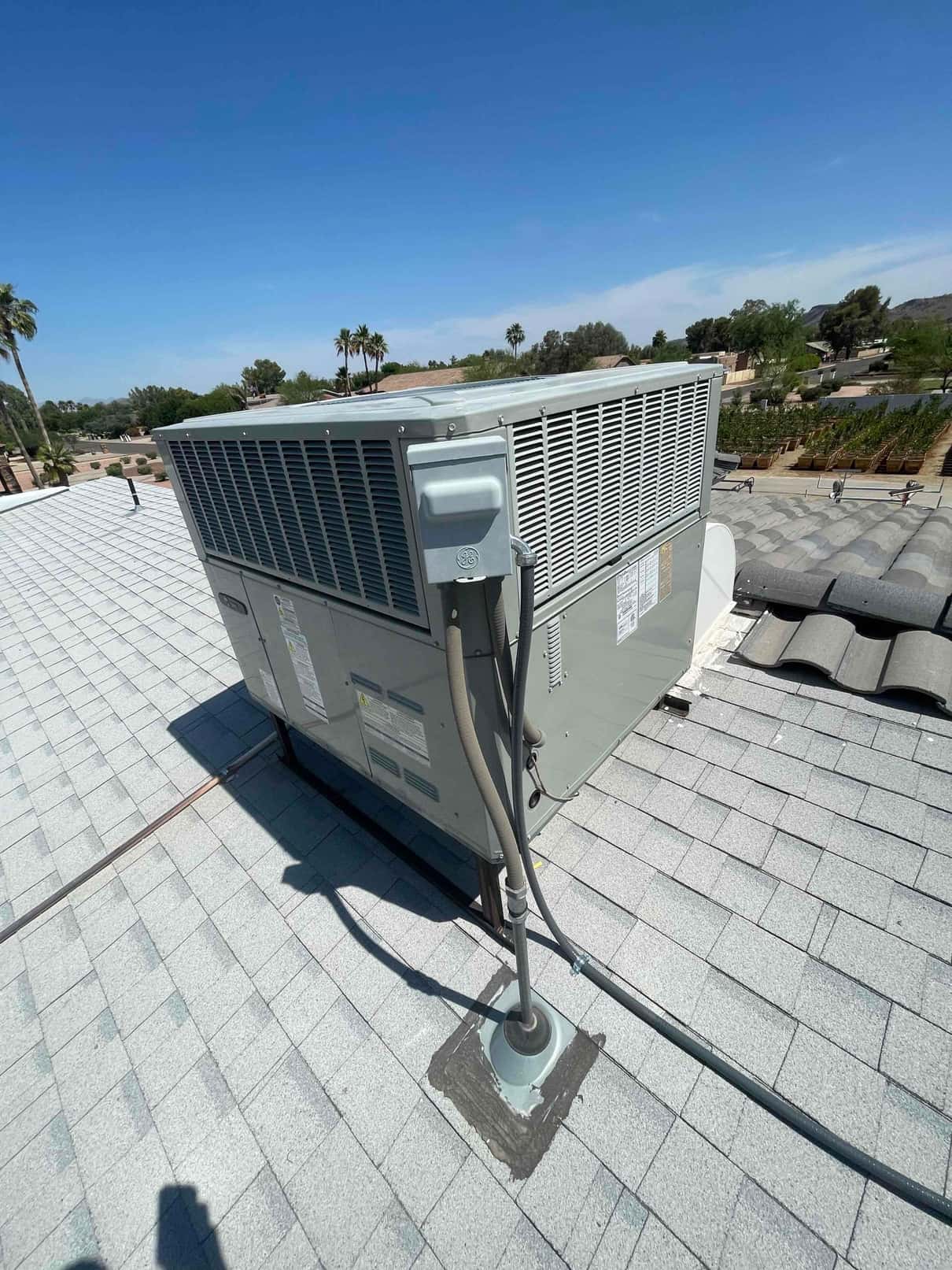 Rooftop package unit installed on rails with sealed roof penetration and flexible conduit connected to the disconnect box.