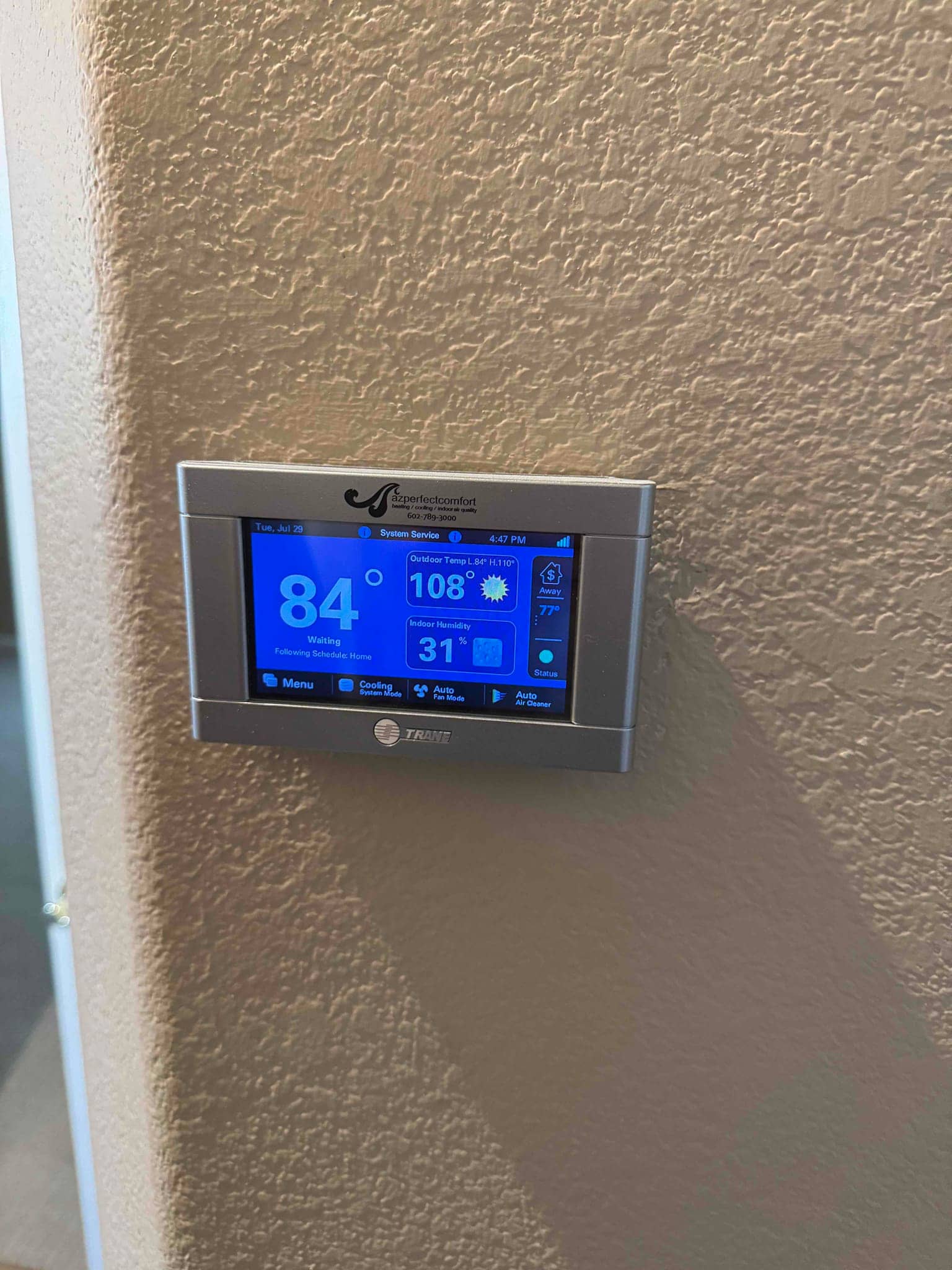 Wall-mounted smart thermostat displays indoor temperature at 84°F with system status and controls visible on the screen.