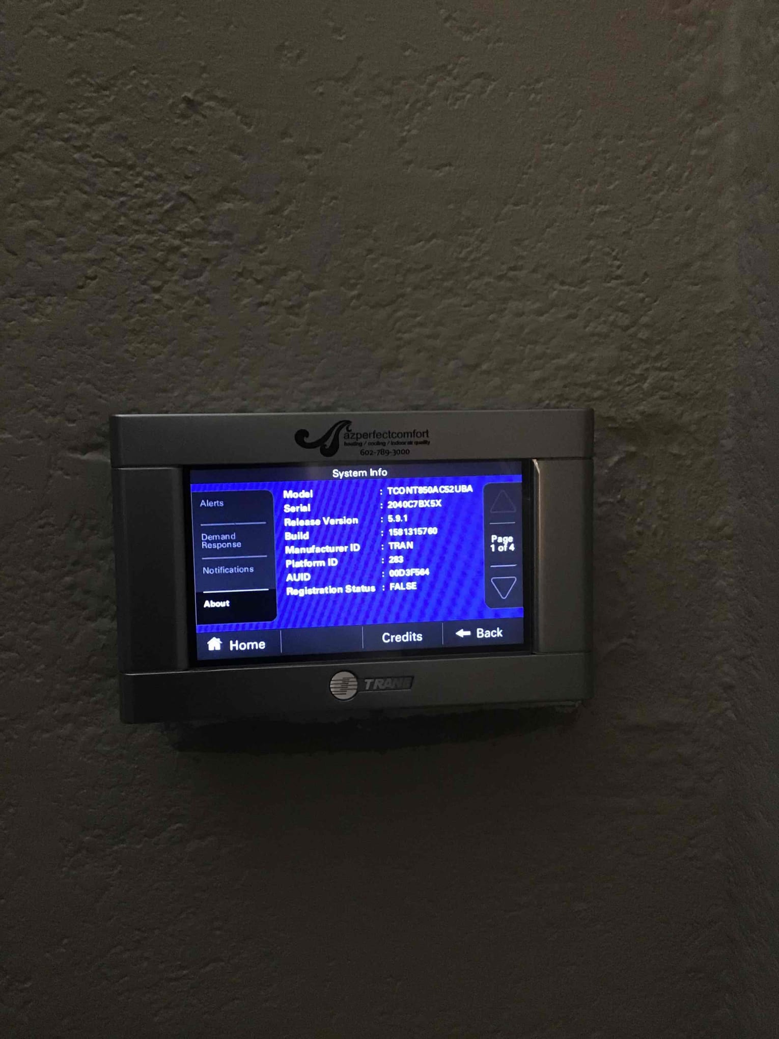Wall-mounted touchscreen thermostat displaying system information after installation, confirming control interface is powered and operational.