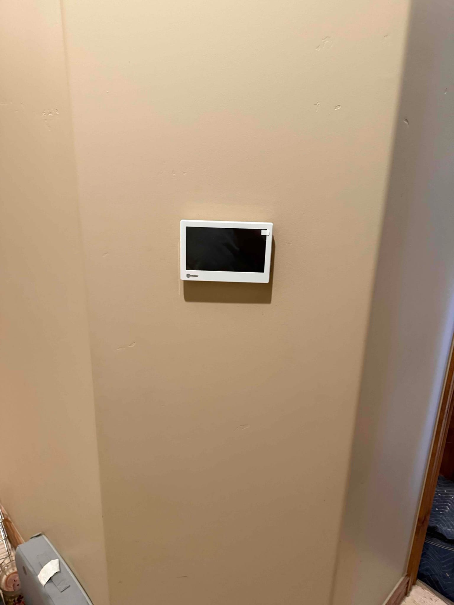 Wall-mounted touchscreen thermostat installed on a finished interior wall, ready for system setup and homeowner control.