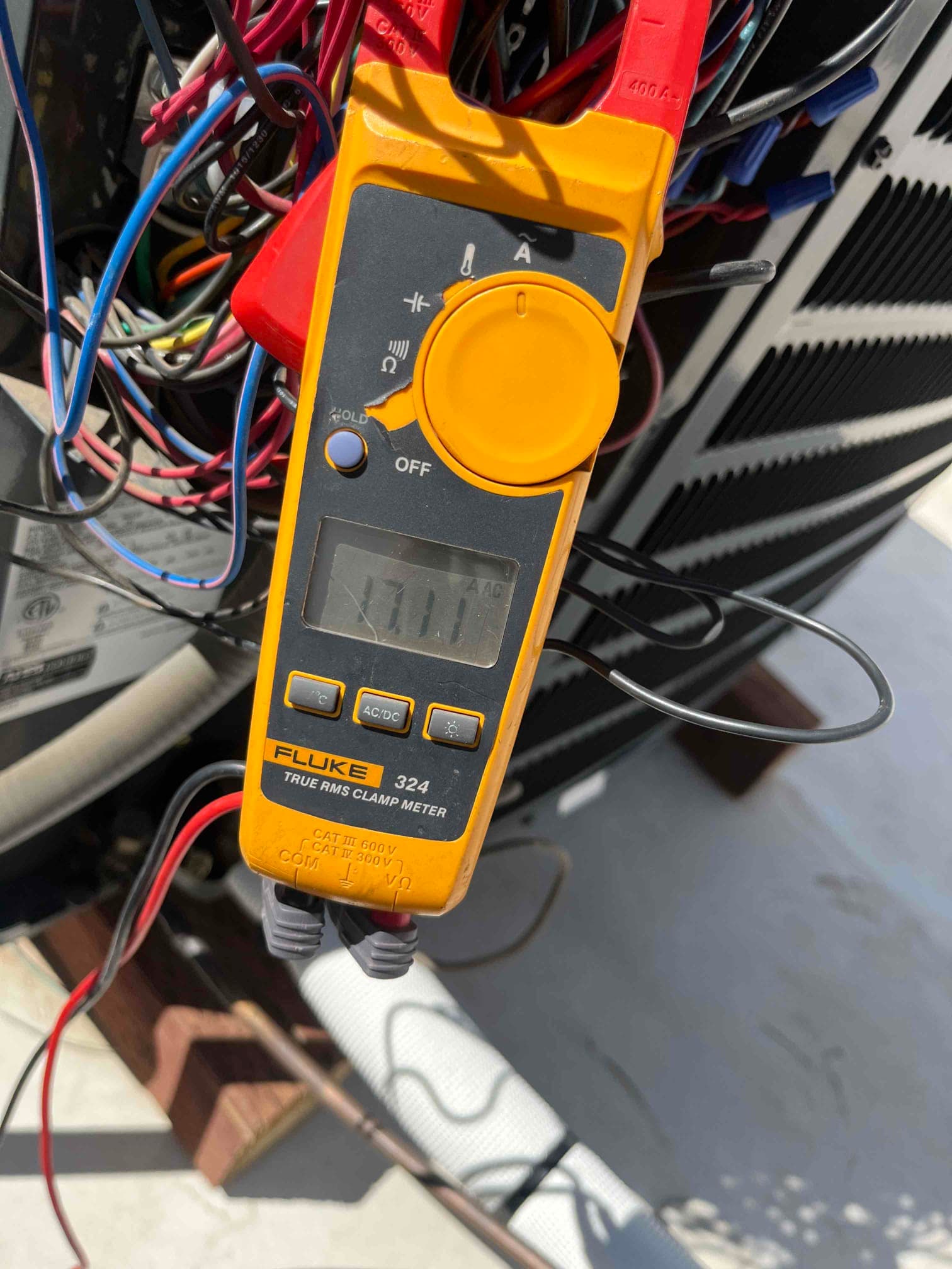 Clamp meter displays 101.7 °F while measuring temperature inside the condenser cabinet wiring area.