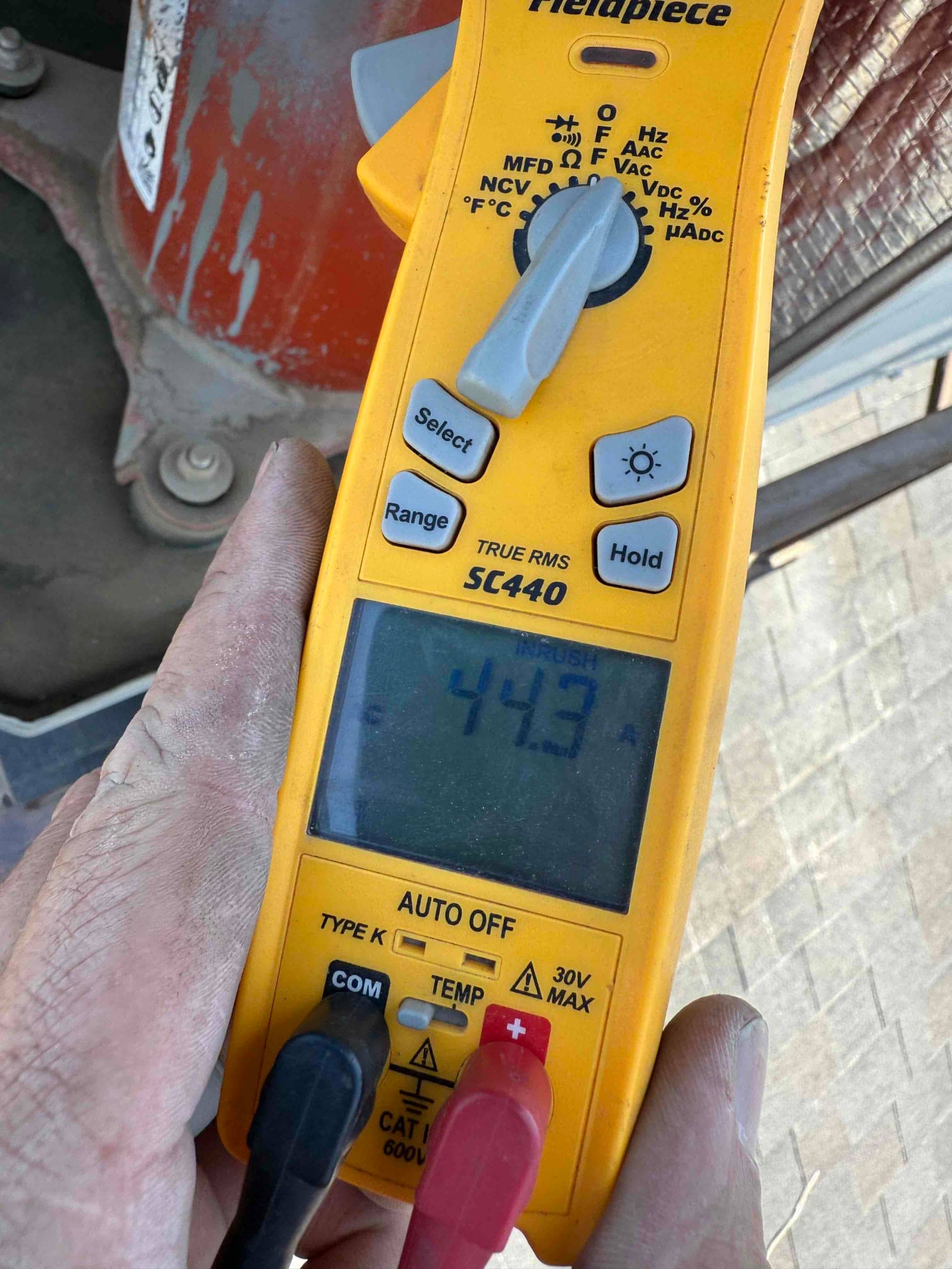 Clamp meter displays 4.3 A while measuring current with the jaw around a conductor at the outdoor unit.