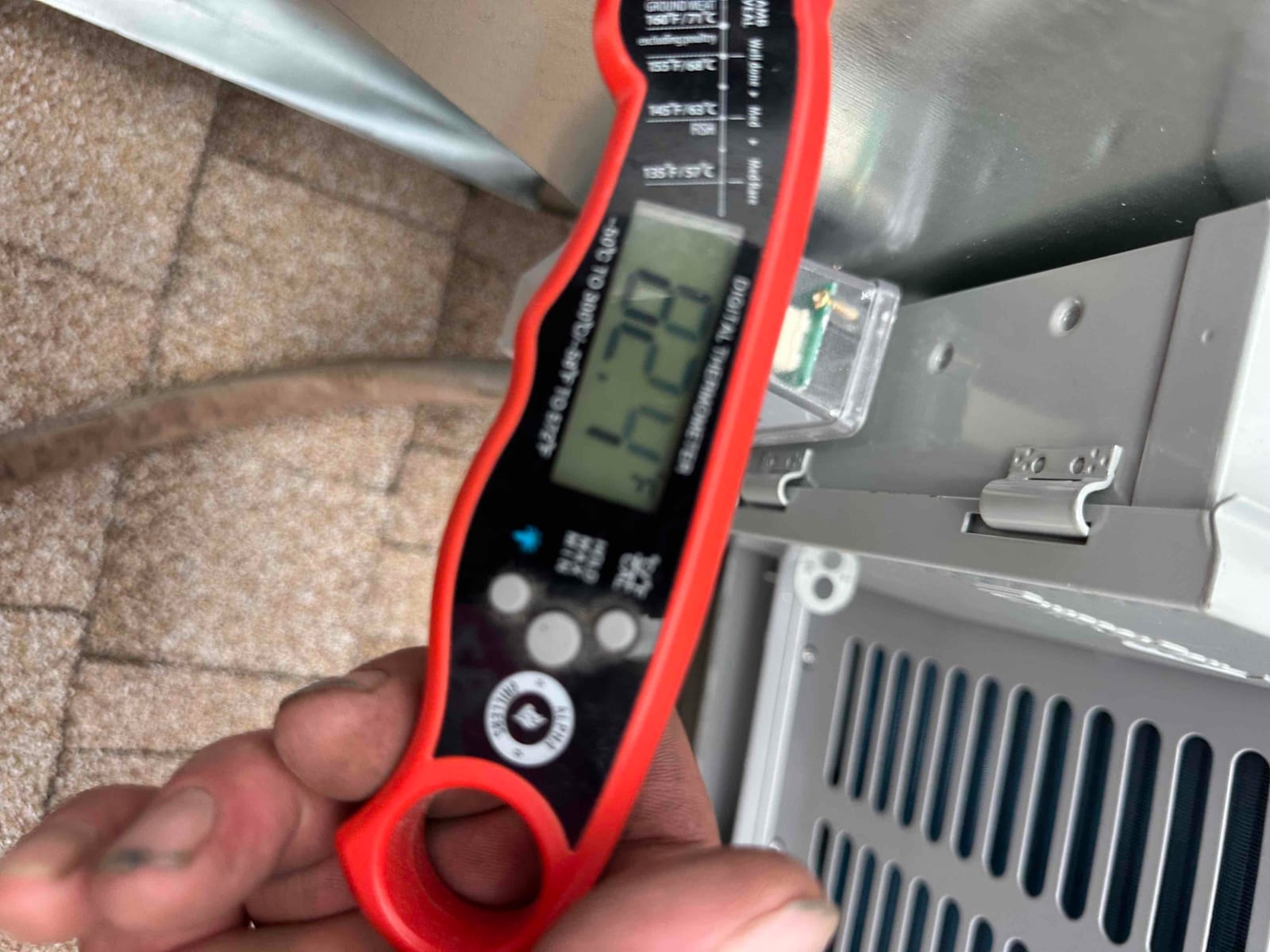 Digital clamp meter measures current on the outdoor unit wiring during commissioning, showing the amperage draw at the disconnect.