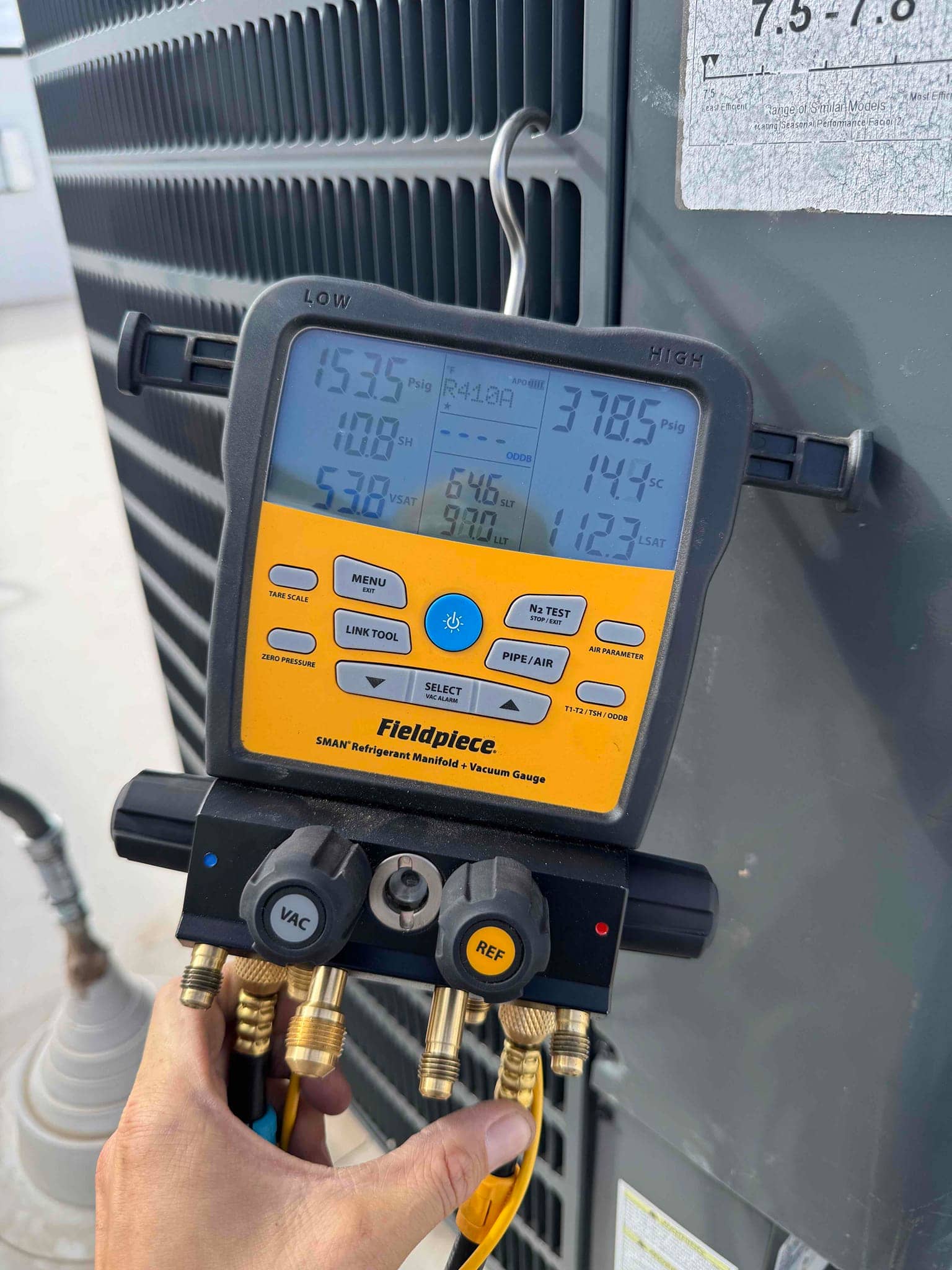 Digital manifold gauge shows 646 microns vacuum during system evacuation, with hoses connected to service ports on the outdoor unit.