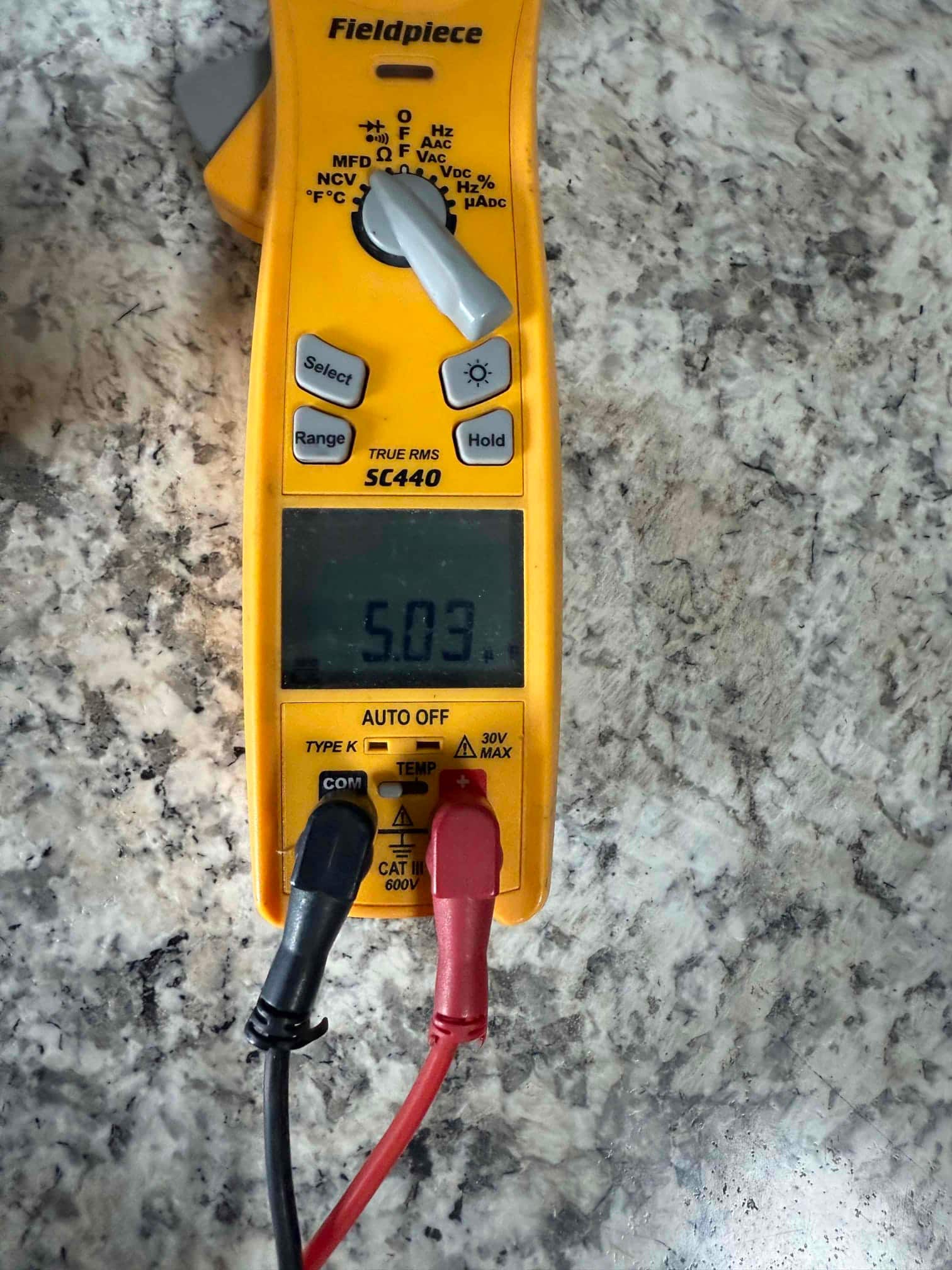 Digital multimeter display shows 5.03 V with red and black test leads connected at the input jacks.