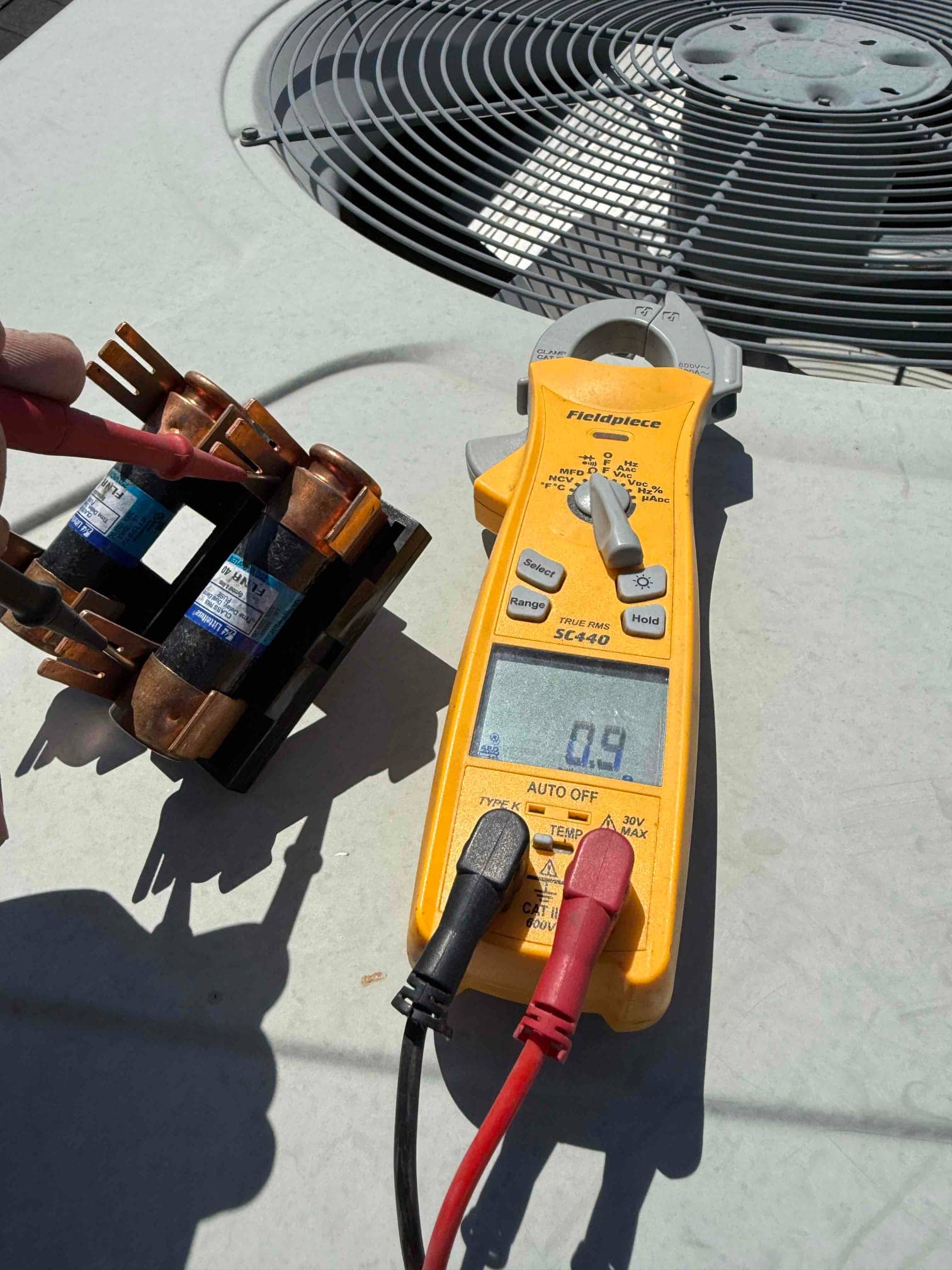 Digital multimeter measures 0.49 MΩ across the contactor coil terminals beside the outdoor condenser unit.