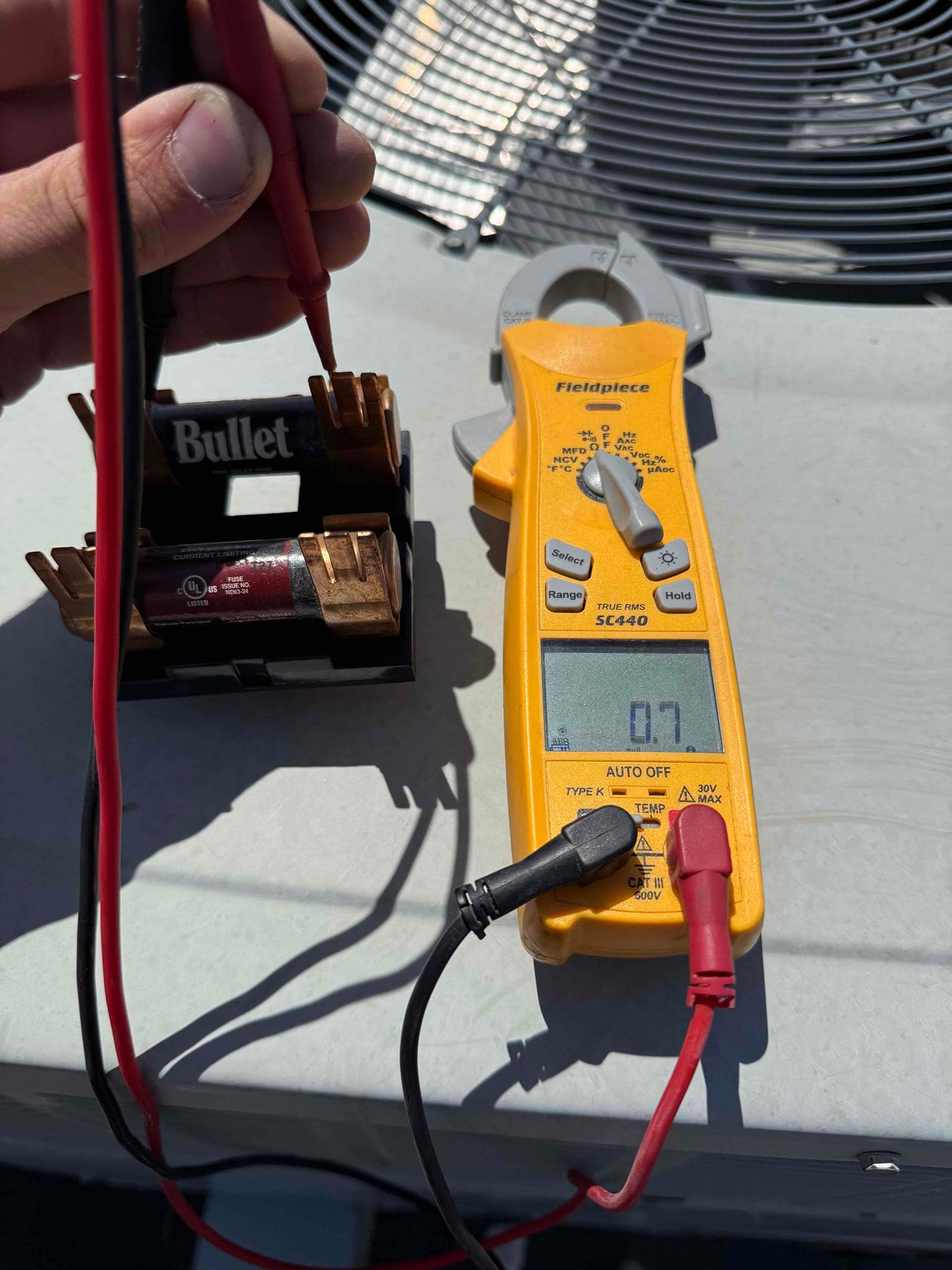 Digital multimeter measures 0.7 V across the leads connected to a battery holder on the unit top.
