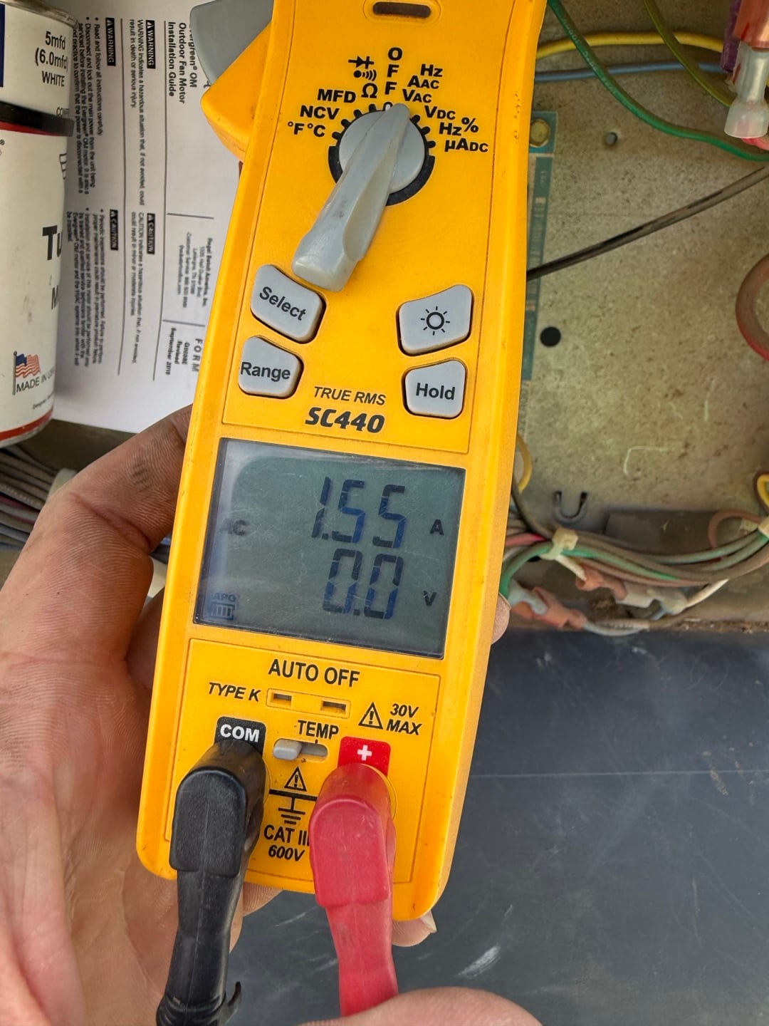 Digital multimeter measures 1.55 V at the red and black test leads inside the condenser control compartment.