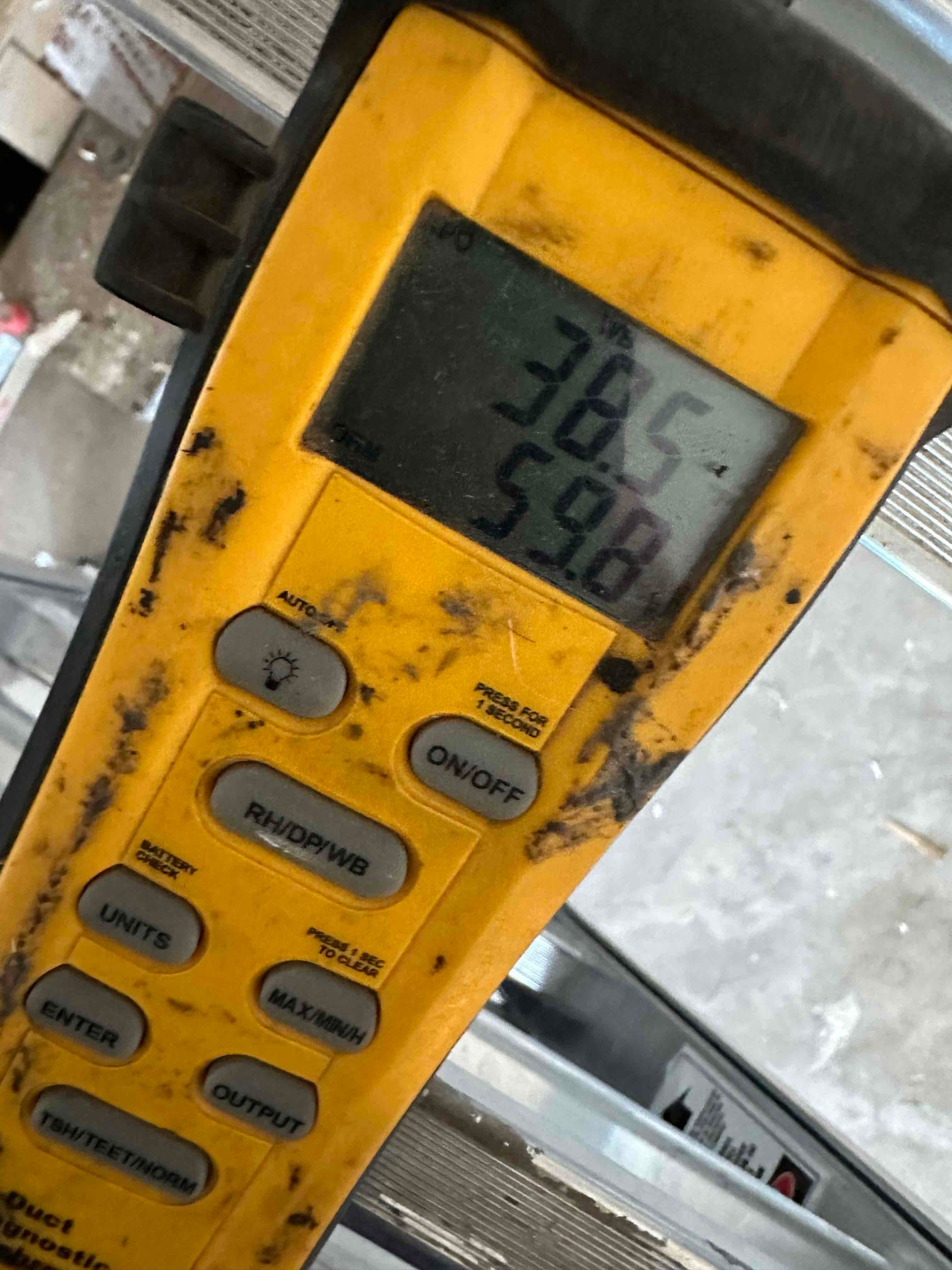 Digital thermometer displays 59.8 degrees, documenting supply air temperature during mini‑split commissioning.