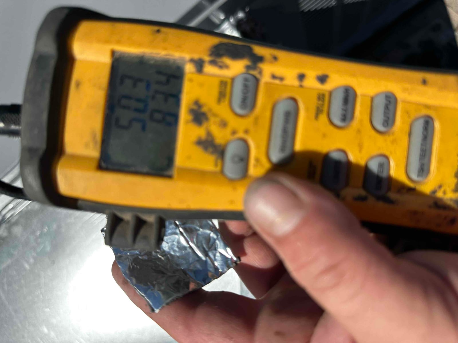 Digital thermometer probe contacts metal duct surface while the display shows a mid-70s Fahrenheit reading during air temperature checks.