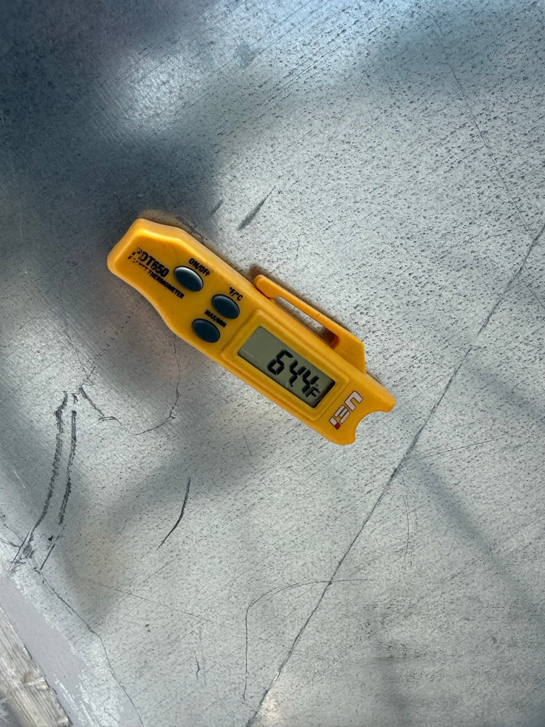 Digital thermometer shows 64.4 °F surface temperature on a sheet metal HVAC component.