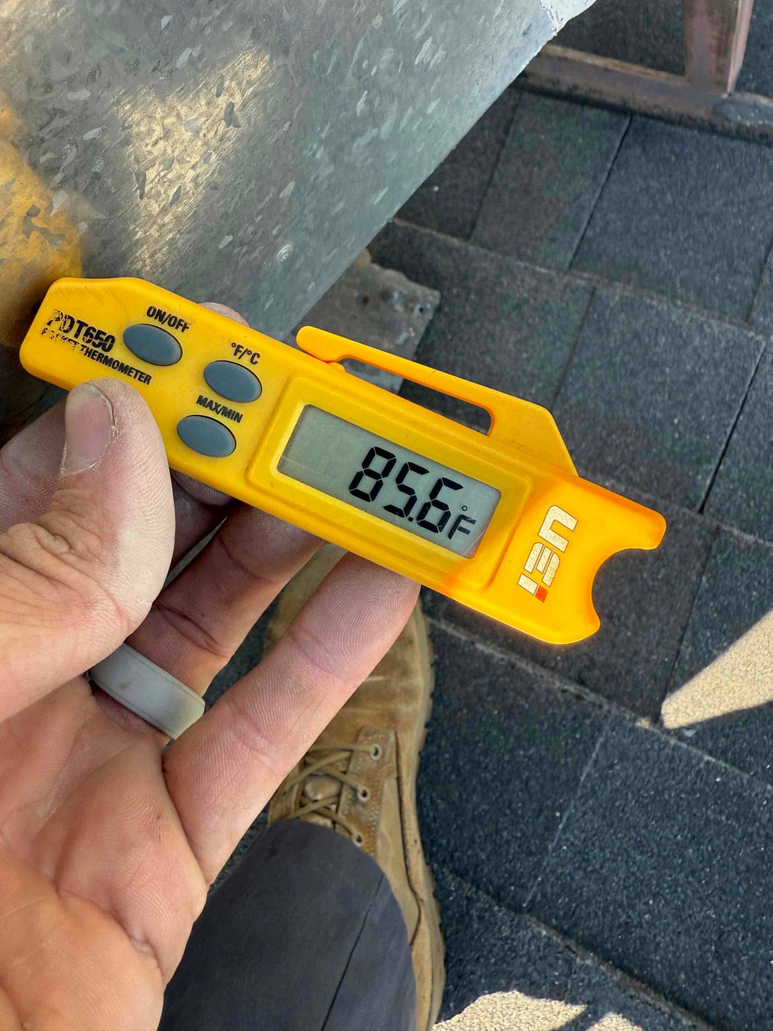 Digital thermometer shows 85.6°F while measuring temperature at the HVAC unit during a system diagnostic.