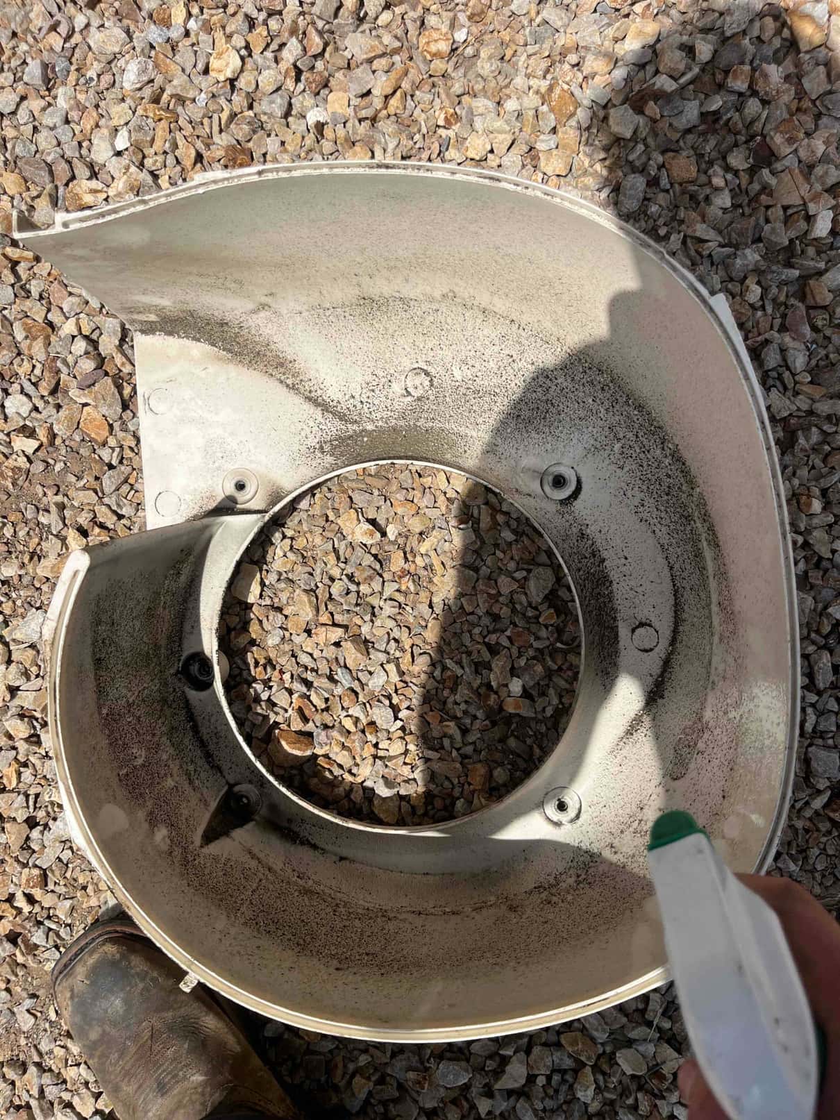 Dirty condenser fan shroud removed from the outdoor unit, showing dust accumulation on the inner surface before cleaning.