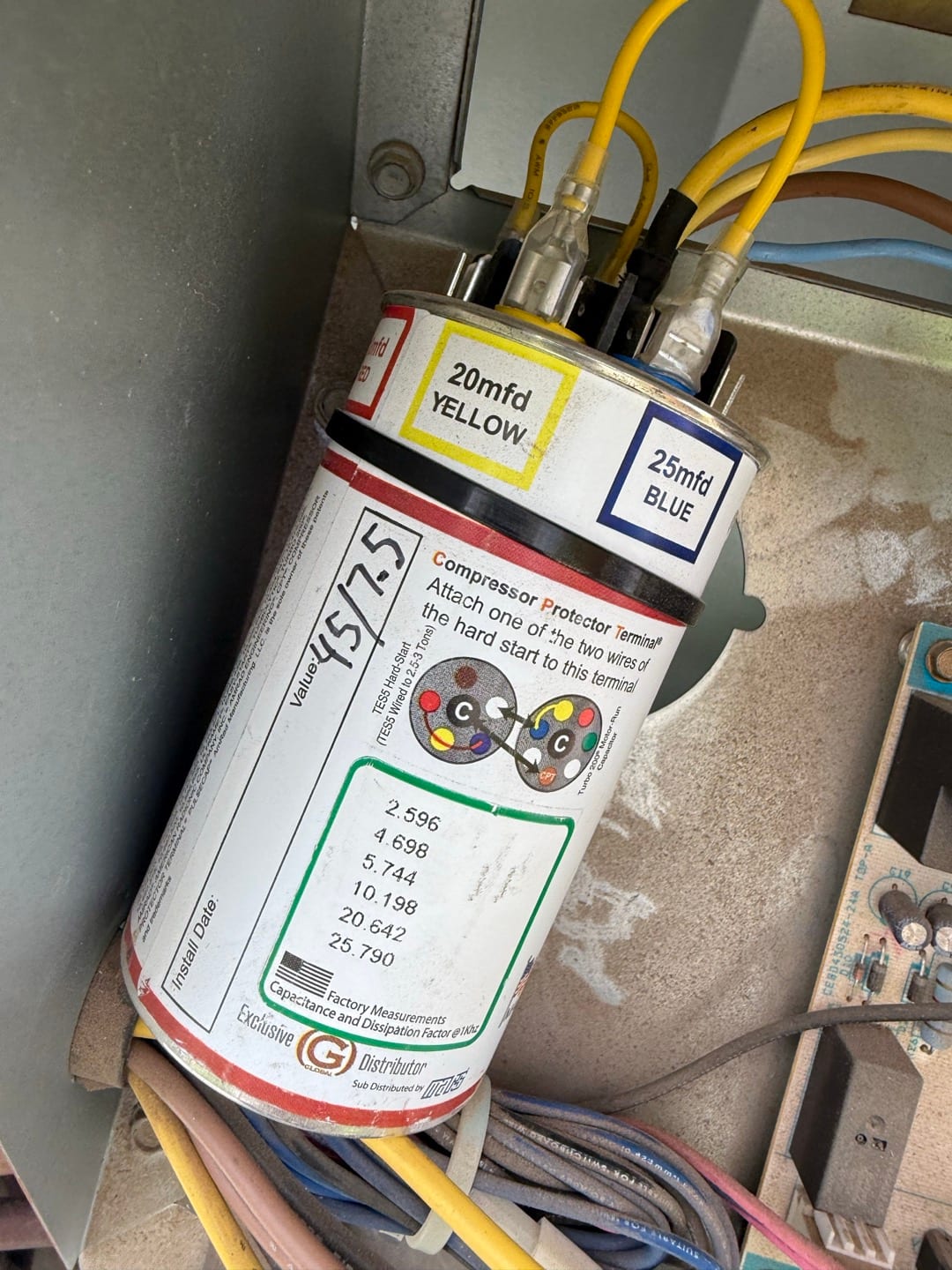 Dual-run capacitor rated 45/5 μF installed in condenser, with labeled yellow 20 μF and blue 25 μF terminals and connected wiring.