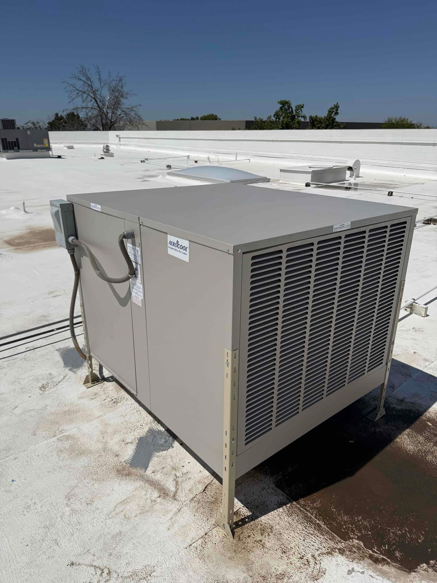 Evaporative cooler installed on rooftop with electrical whip connected and unit leveled on support legs.