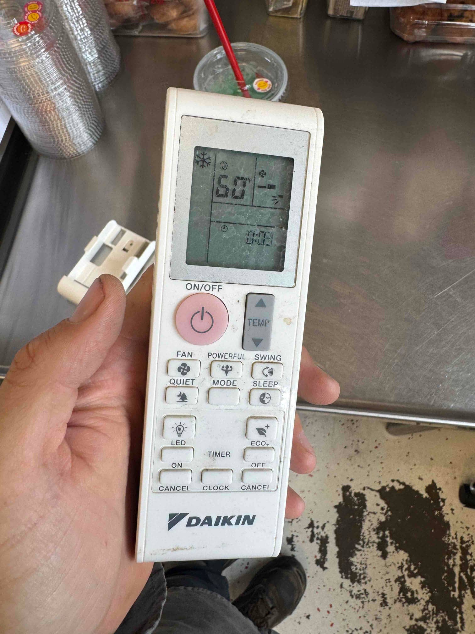 Handheld air conditioning remote control shows a 60 °F set temperature with cooling mode active on the display.