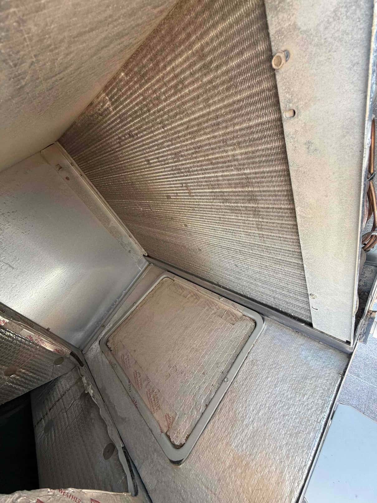 Indoor evaporator coil and cabinet interior shown with metal fins and insulated access panel during diagnostic evaluation.