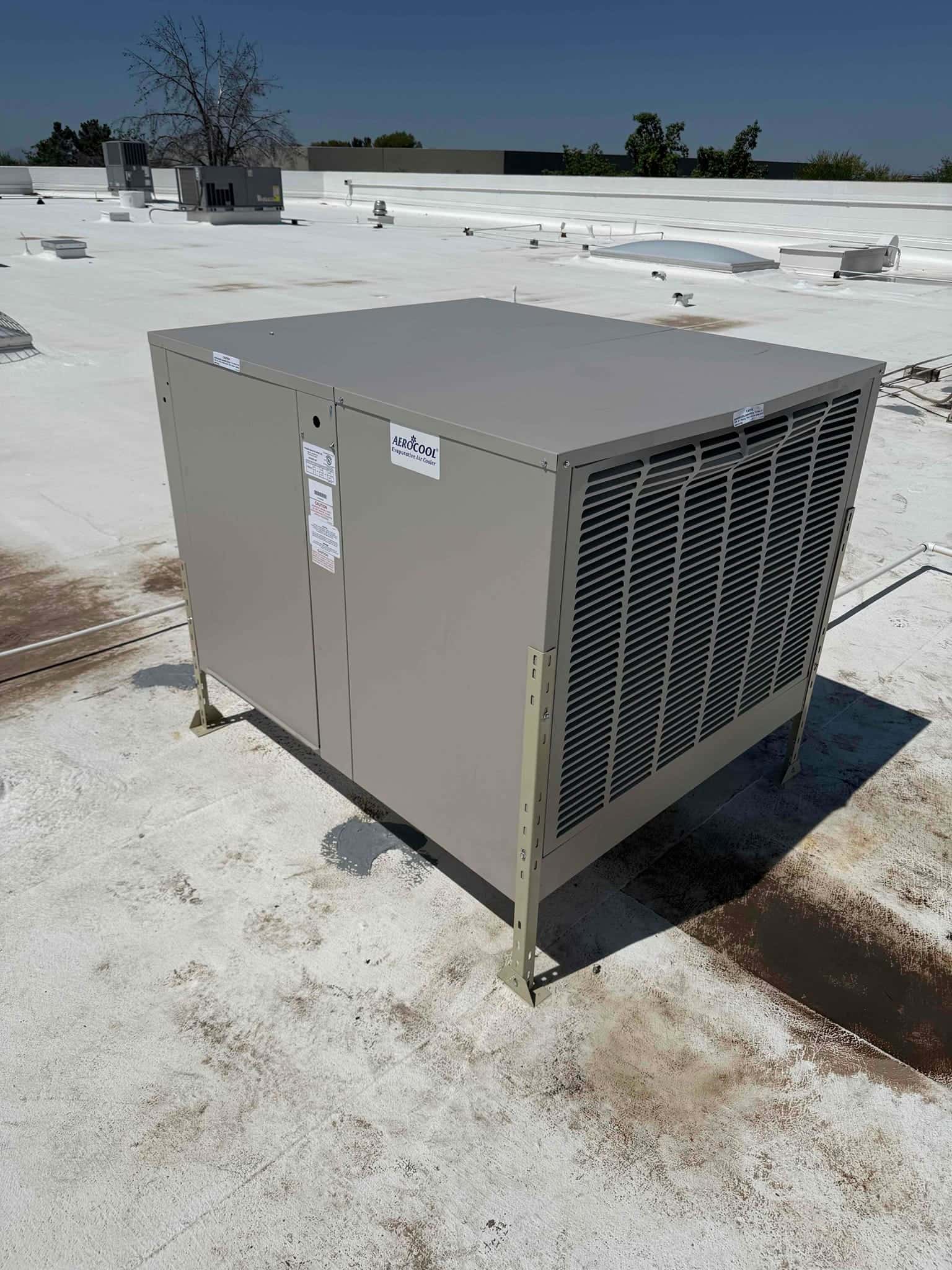New rooftop evaporative cooler installed on raised supports, aligned and secured on the roof with proper clearances.