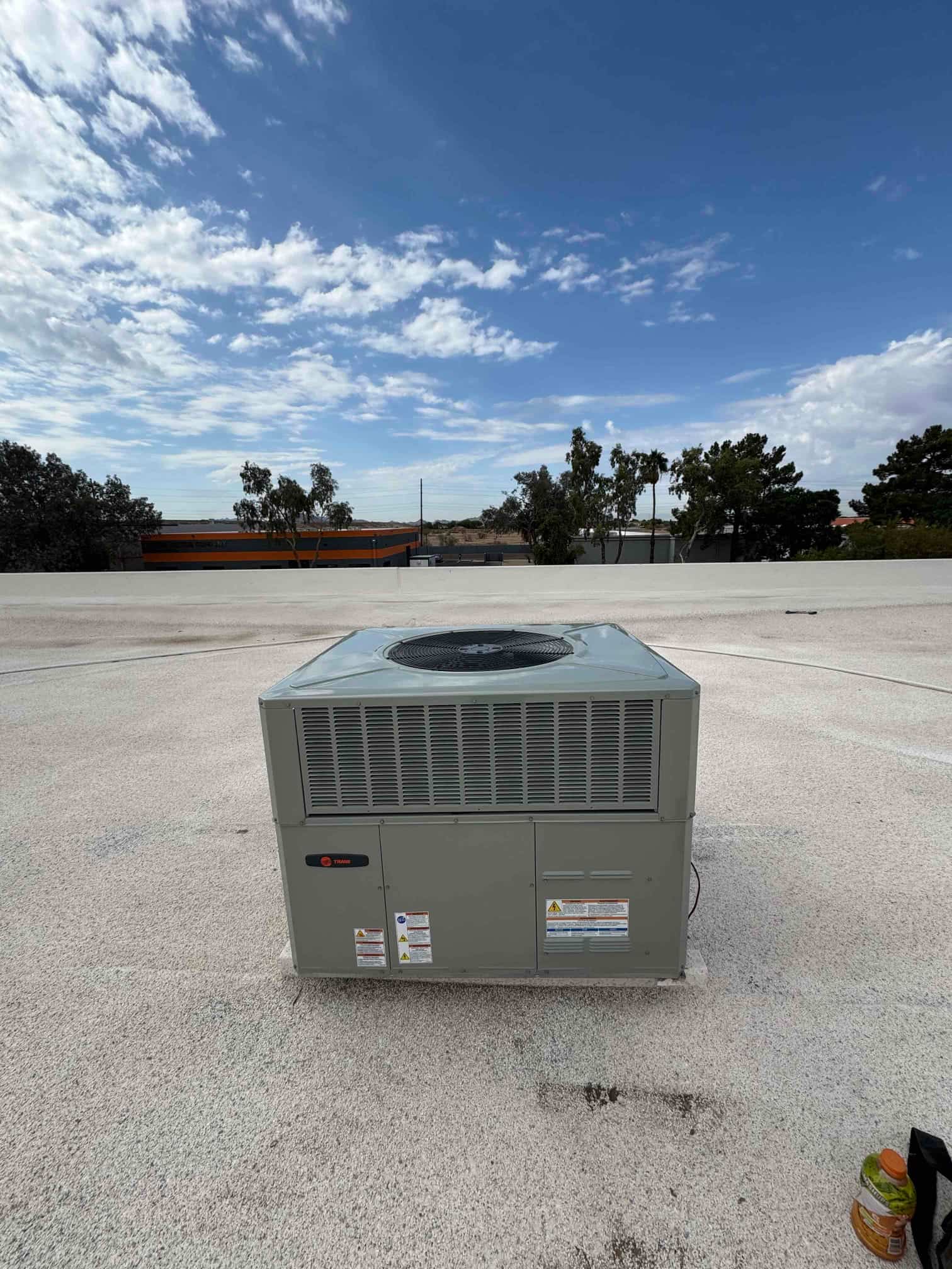New rooftop packaged HVAC unit set on a level curb with condenser fan at the top and access panels closed.