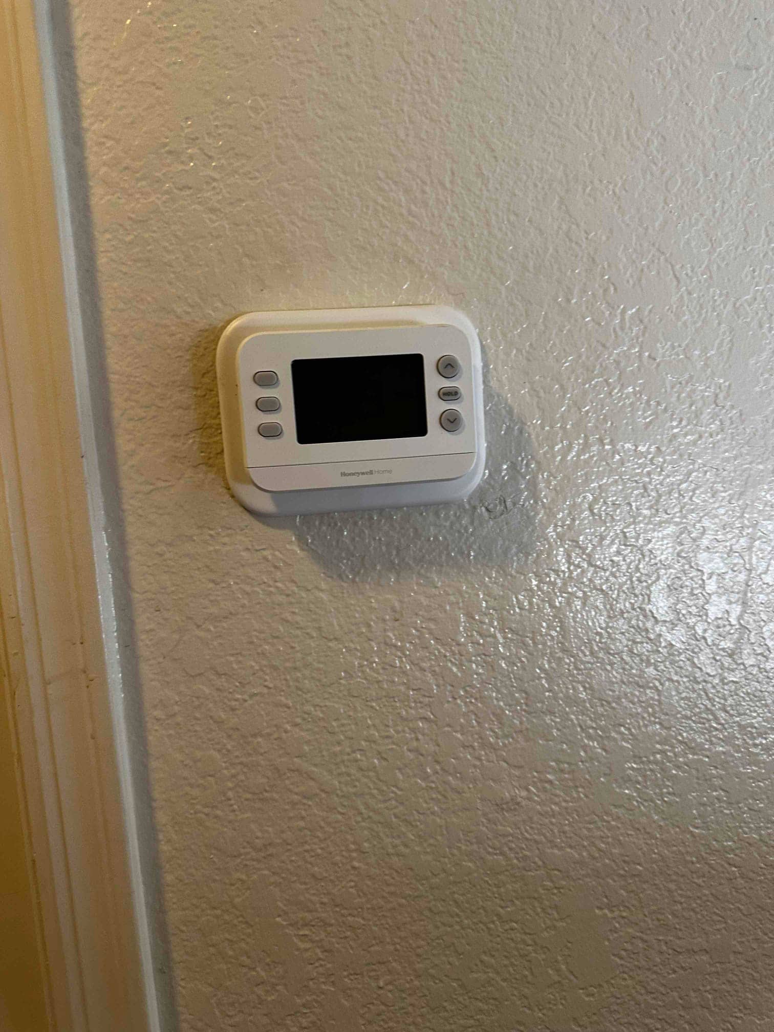 New wall-mounted thermostat installed and leveled, ready to control the HVAC system.