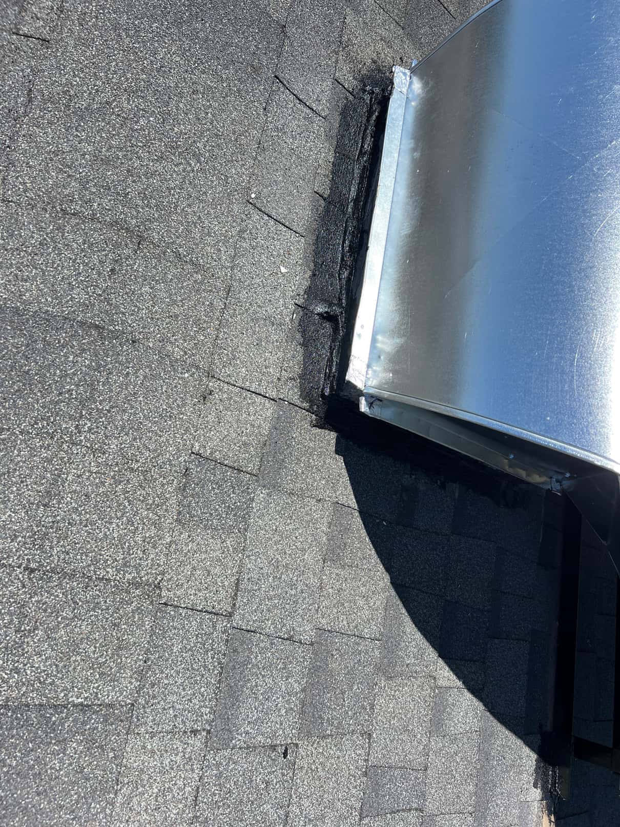 Roof penetration for sheet-metal duct curb sealed with roofing mastic where it meets asphalt shingles.
