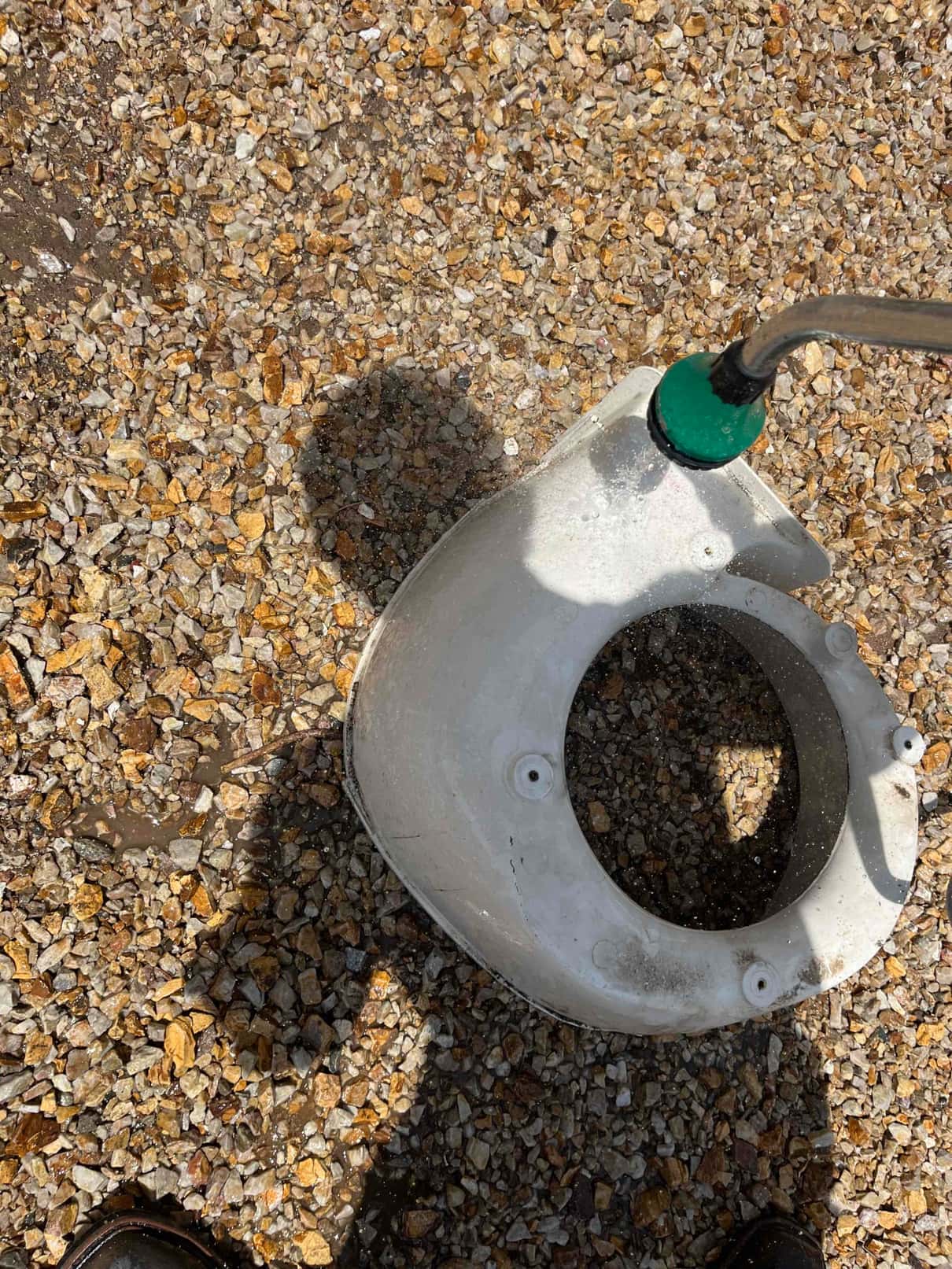 Technician pressure-washes a removable HVAC fan shroud or housing component outdoors, rinsing debris from the white plastic part.