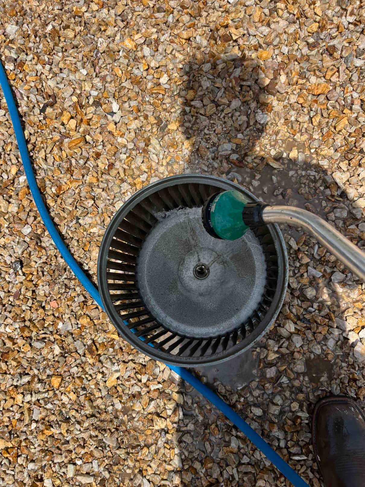 Technician rinses a blower wheel with a hose, removing dust and debris from the fins during a super clean.