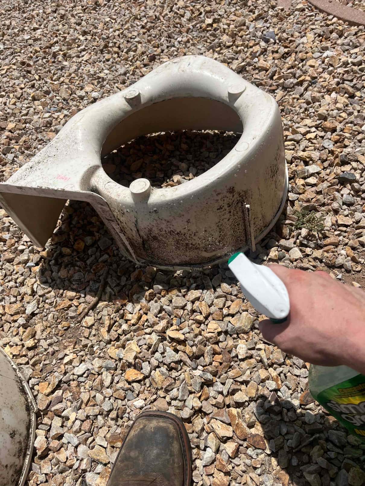 Technician sprays cleaner onto a dirty outdoor condenser fan shroud removed from the unit for a thorough cleaning.