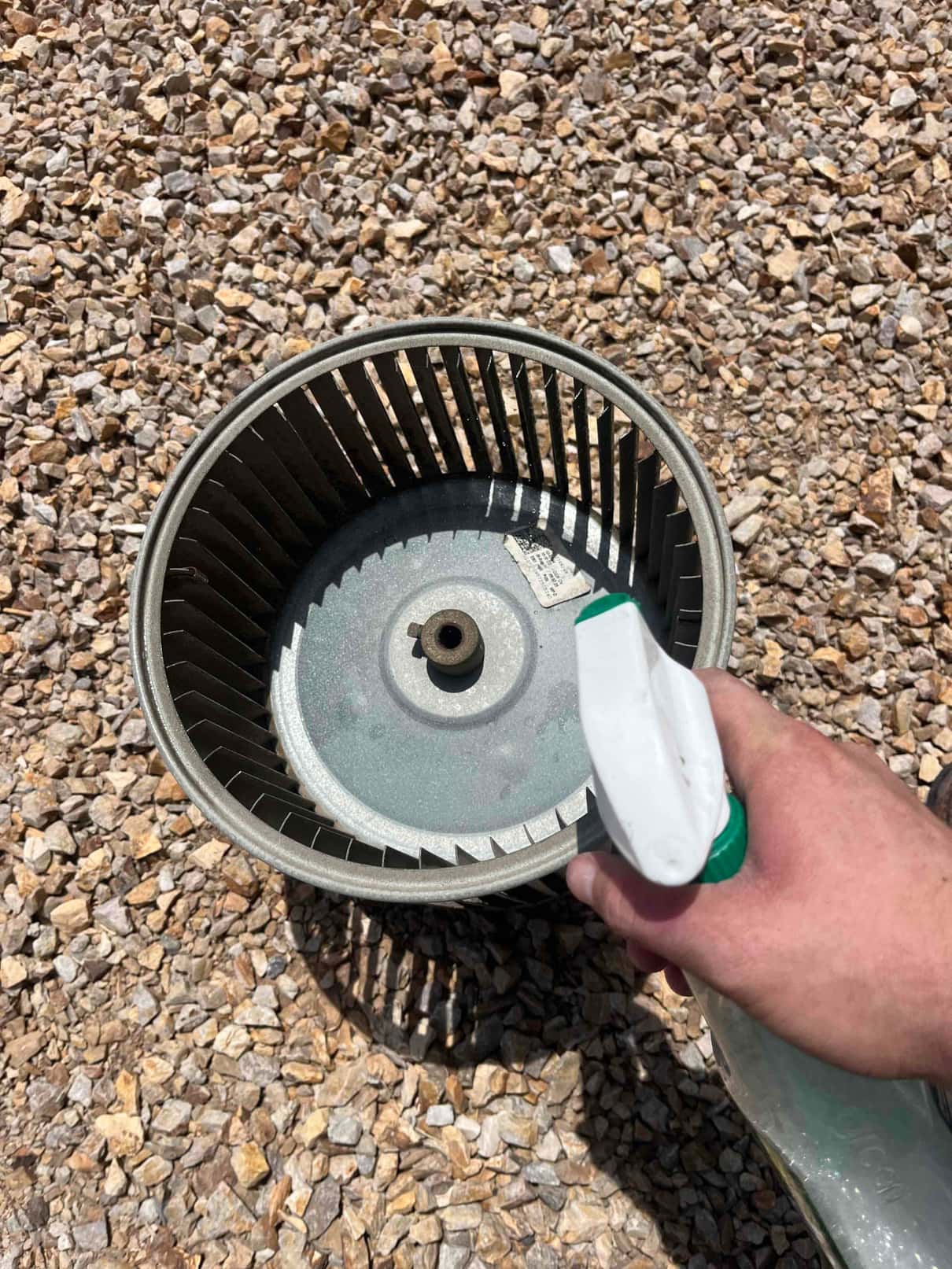 Technician sprays cleaner onto a removed blower wheel and housing for a thorough super clean service.