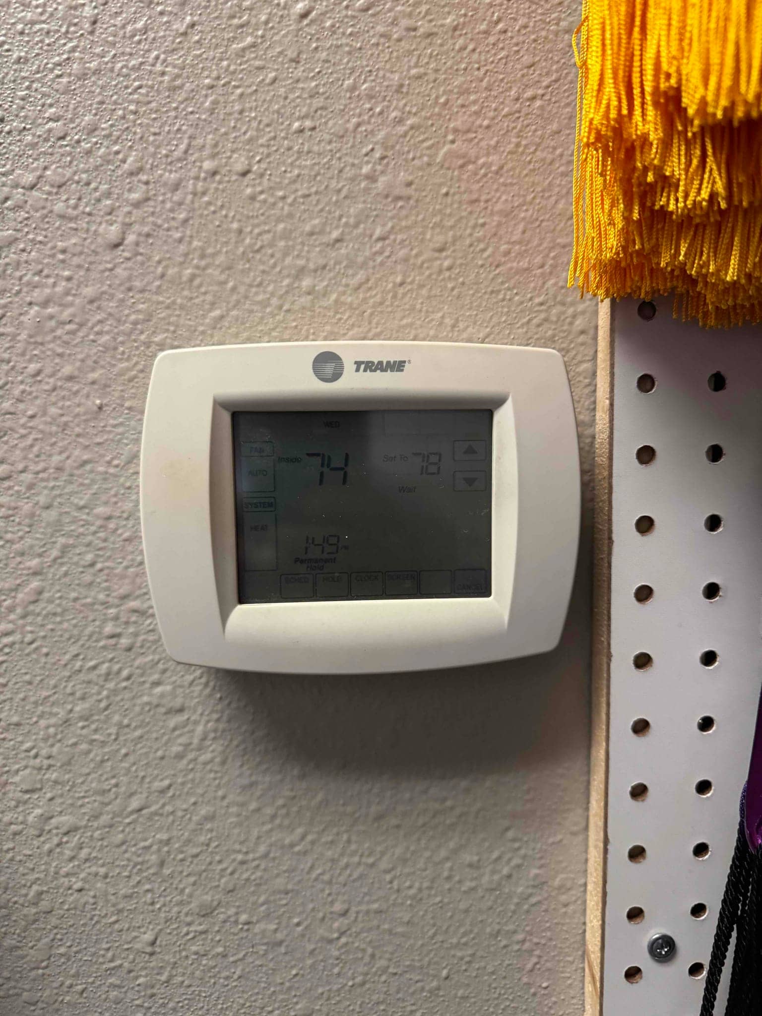 Wall-mounted programmable thermostat displays indoor temperature and setpoint during system setup in the finished installation area.