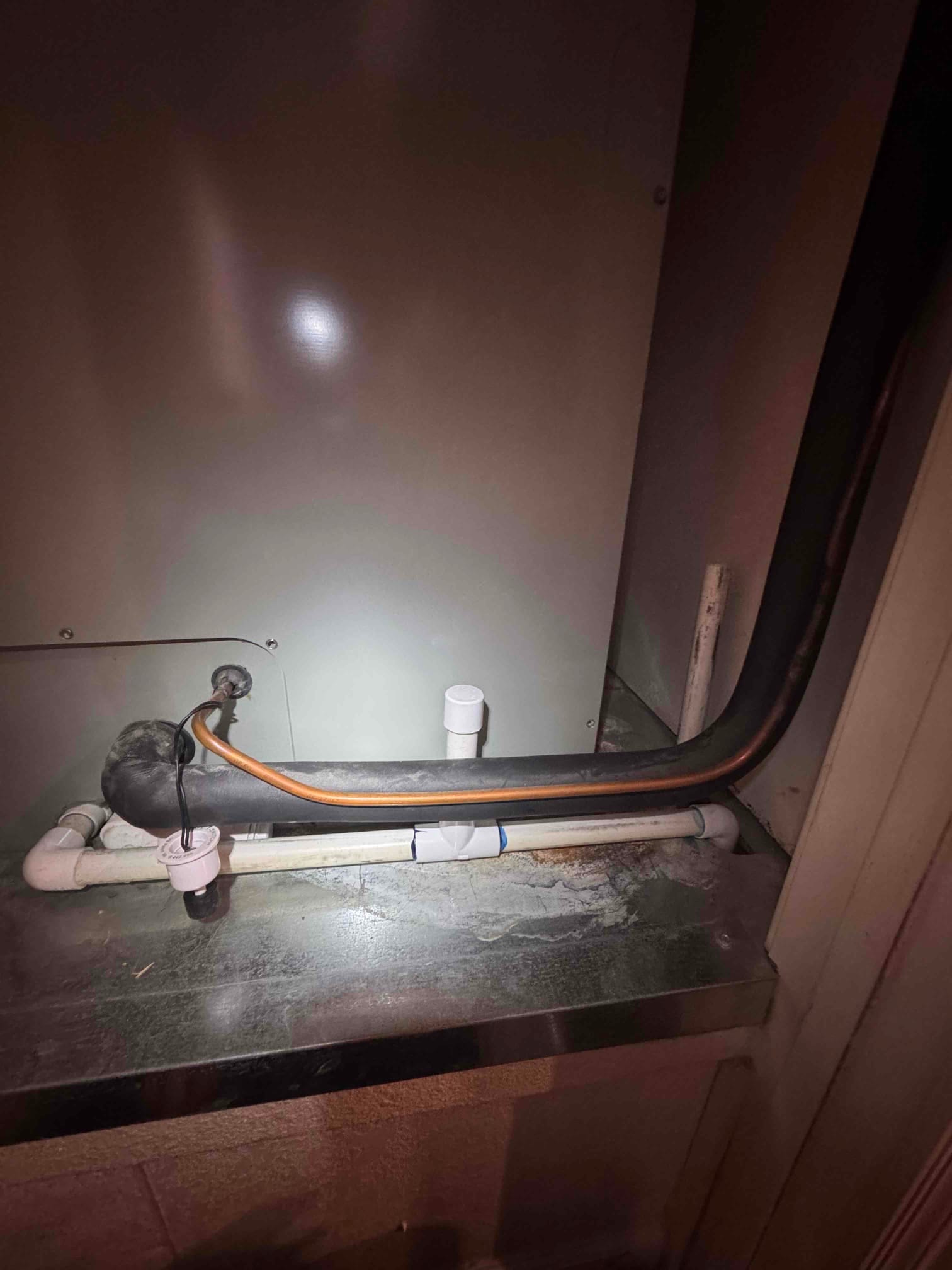 Air handler condensate drain assembly with cleanout tee and trap, alongside insulated refrigerant lines, after drain line repair and flush.