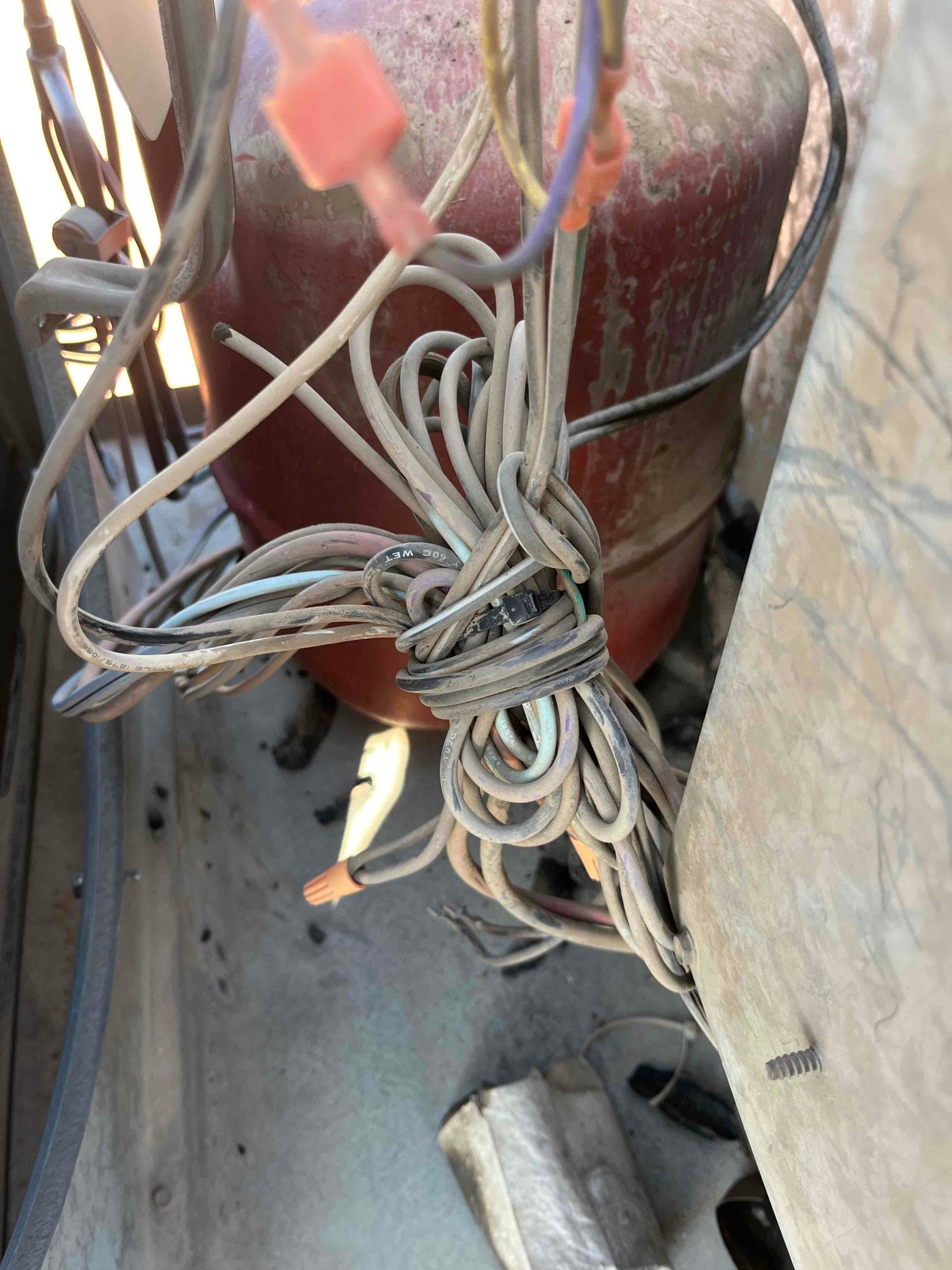 Bundle of electrical control wires twisted and taped inside the outdoor condenser cabinet near the compressor housing.