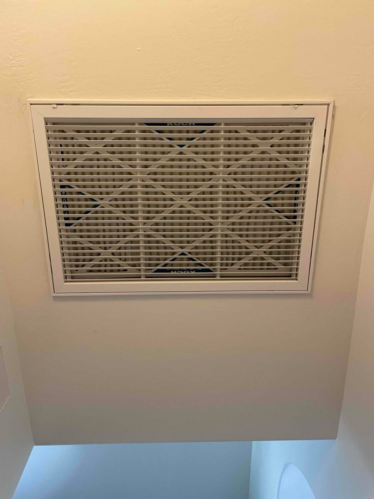 Ceiling-mounted return air grille with a new pleated filter installed and secured within the frame.