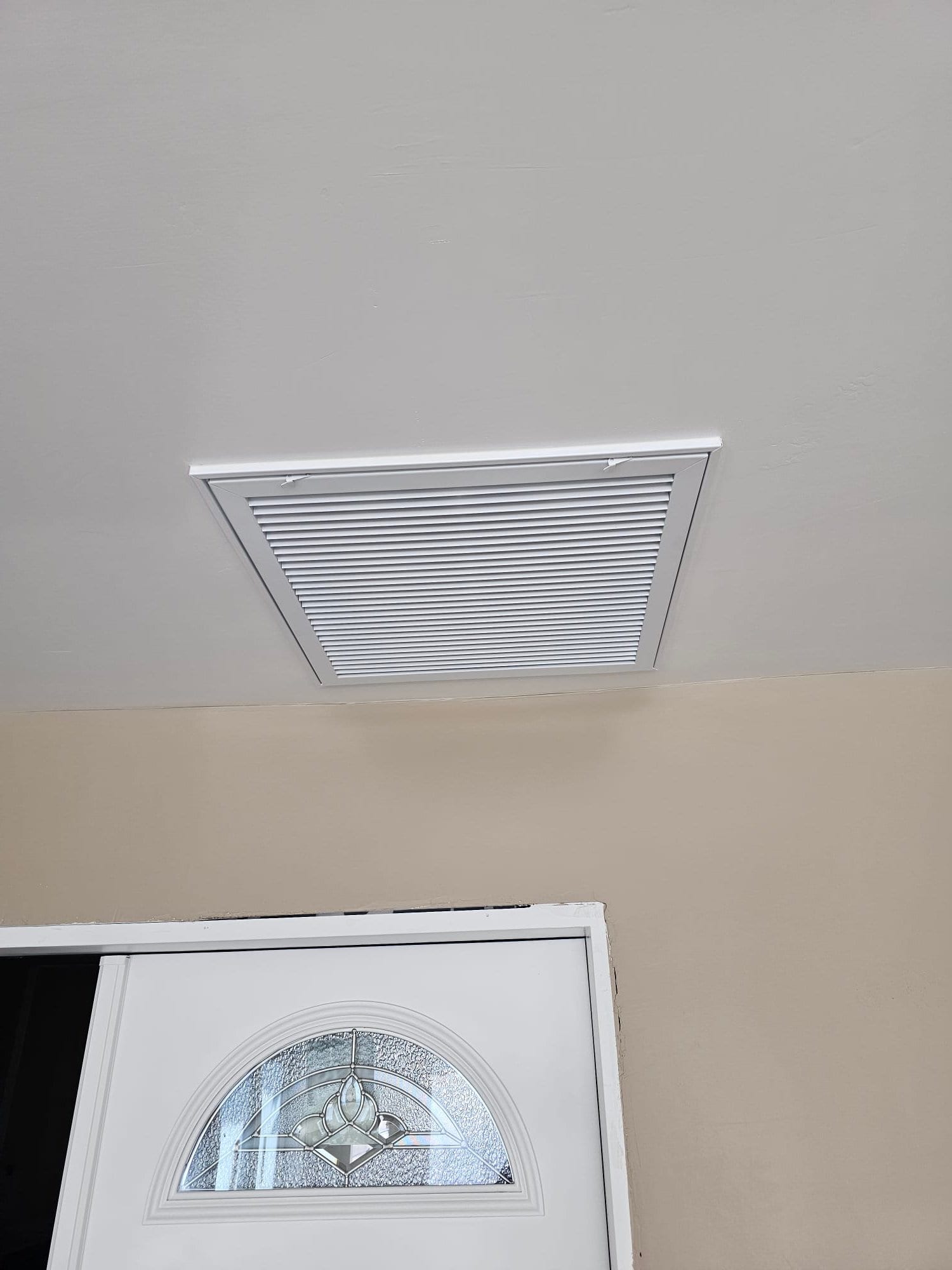 Ceiling return grille installed near the entryway, with clean louvered cover aligned flush to the finished surface.