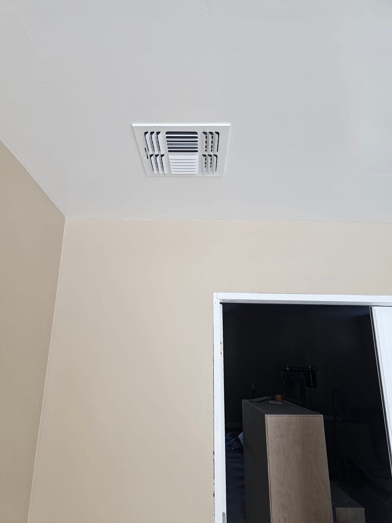 Ceiling supply register freshly installed in a finished room, centered on the ceiling with clean trim around the opening.