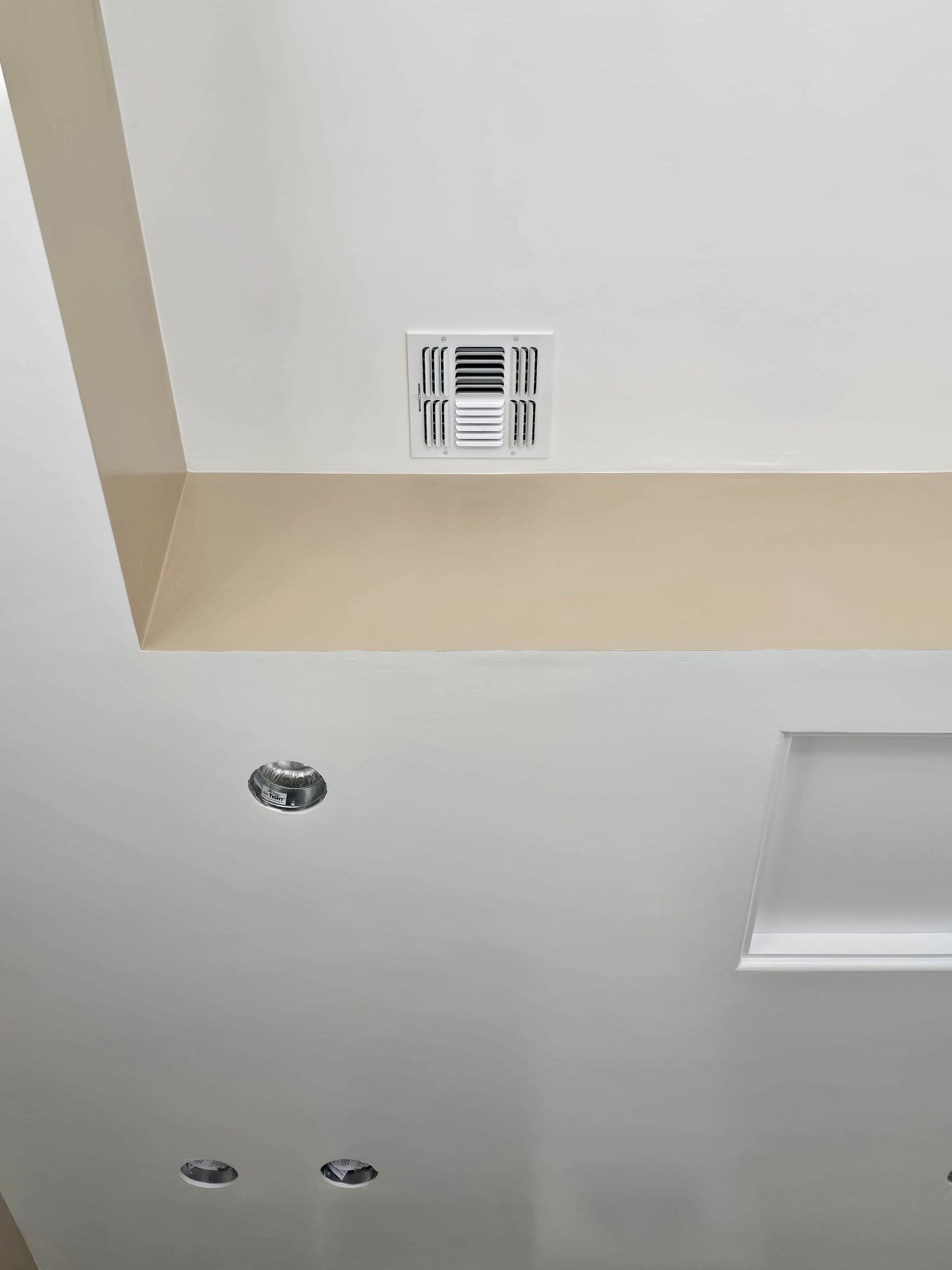 Ceiling supply register installed cleanly, aligned with recessed lighting and trim, showing finished ductwork termination at the living space.