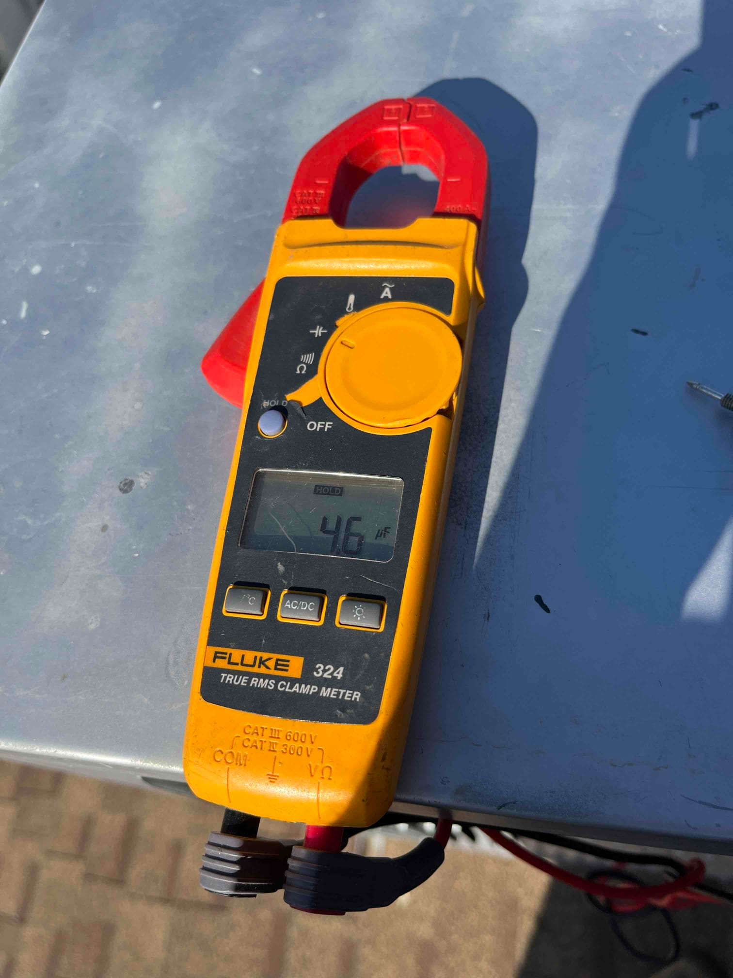 Clamp meter display shows 4.6 A while connected to leads on HVAC equipment during diagnostic testing.