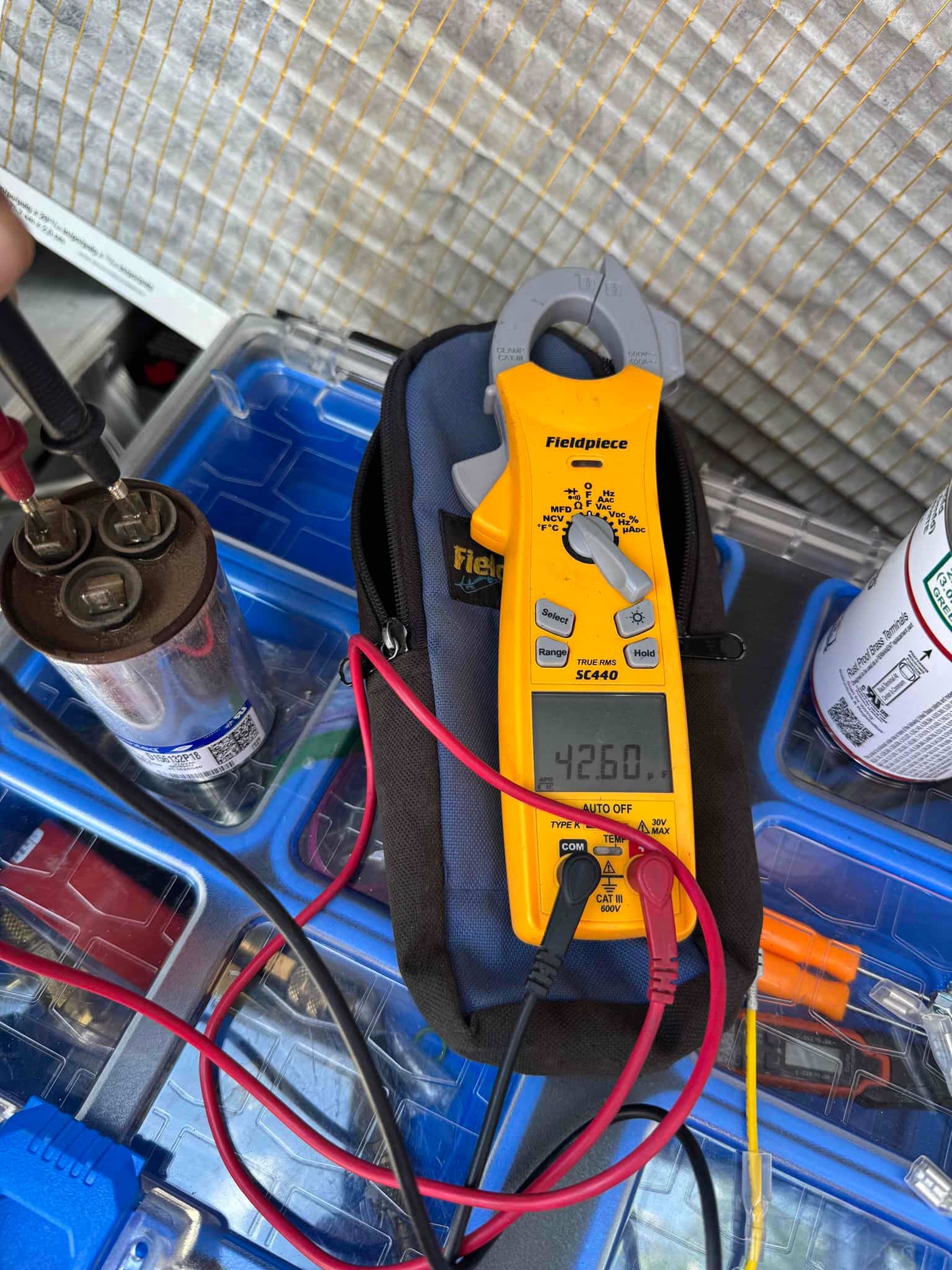 Clamp meter measures 42.60 μF on the removed run capacitor, with test leads connected across its terminals.