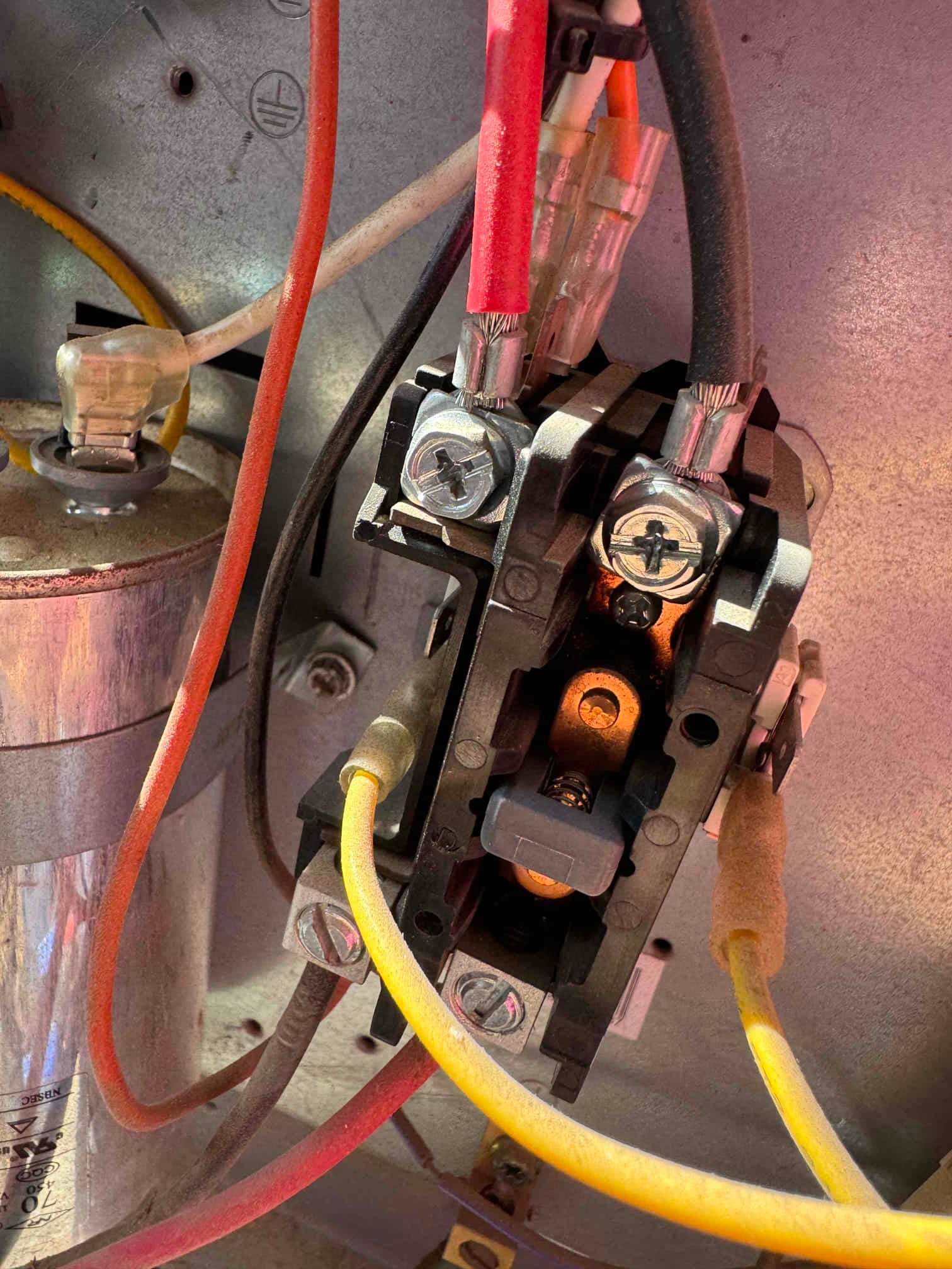 Contactor with connected low-voltage and high-voltage wires inside the condenser compartment, adjacent to a cylindrical run capacitor.