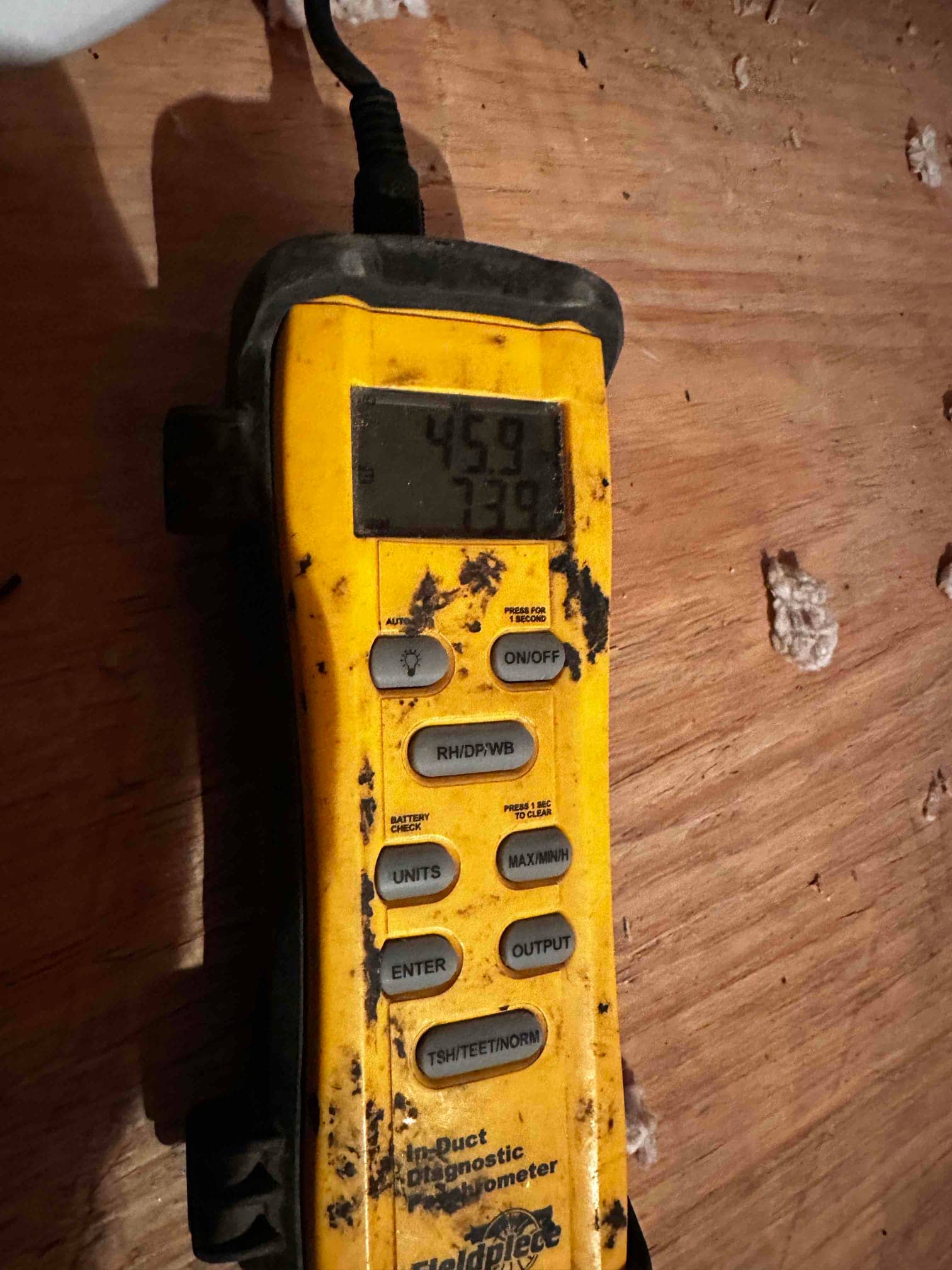 Digital in-duct thermometer displays 45.9 and 73.9 degrees during air-side commissioning to document supply and return temperatures.