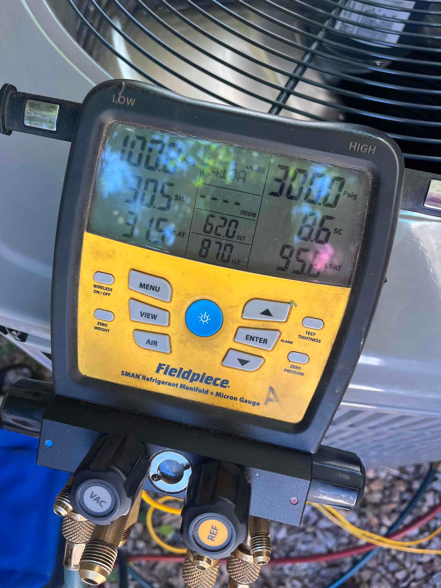 Digital manifold connected to the condenser shows operating pressures with superheat and subcooling during system commissioning.