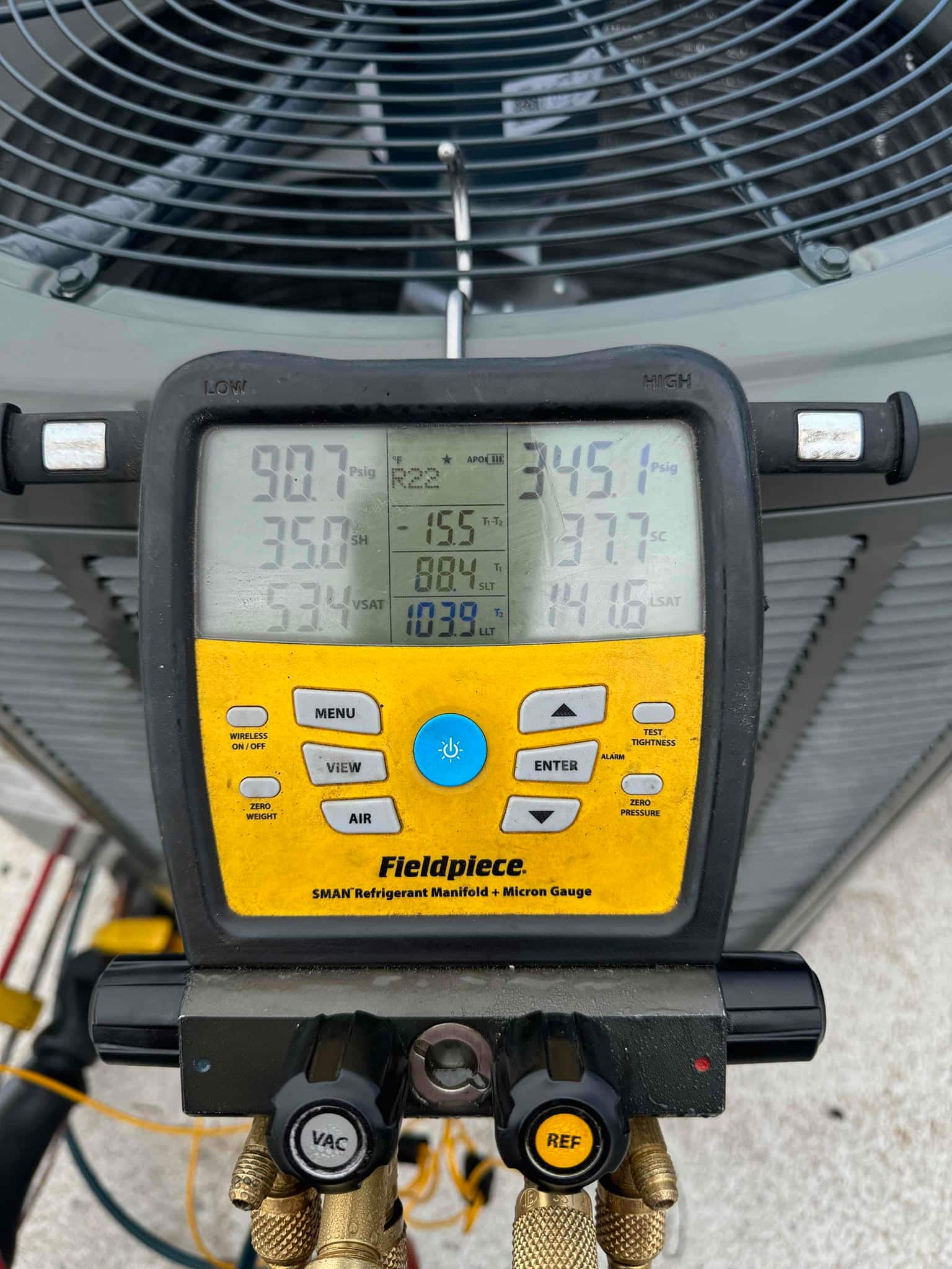 Digital manifold connected at the outdoor condenser shows operating pressures of 90.7 PSI suction and 345.1 PSI liquid during commissioning.