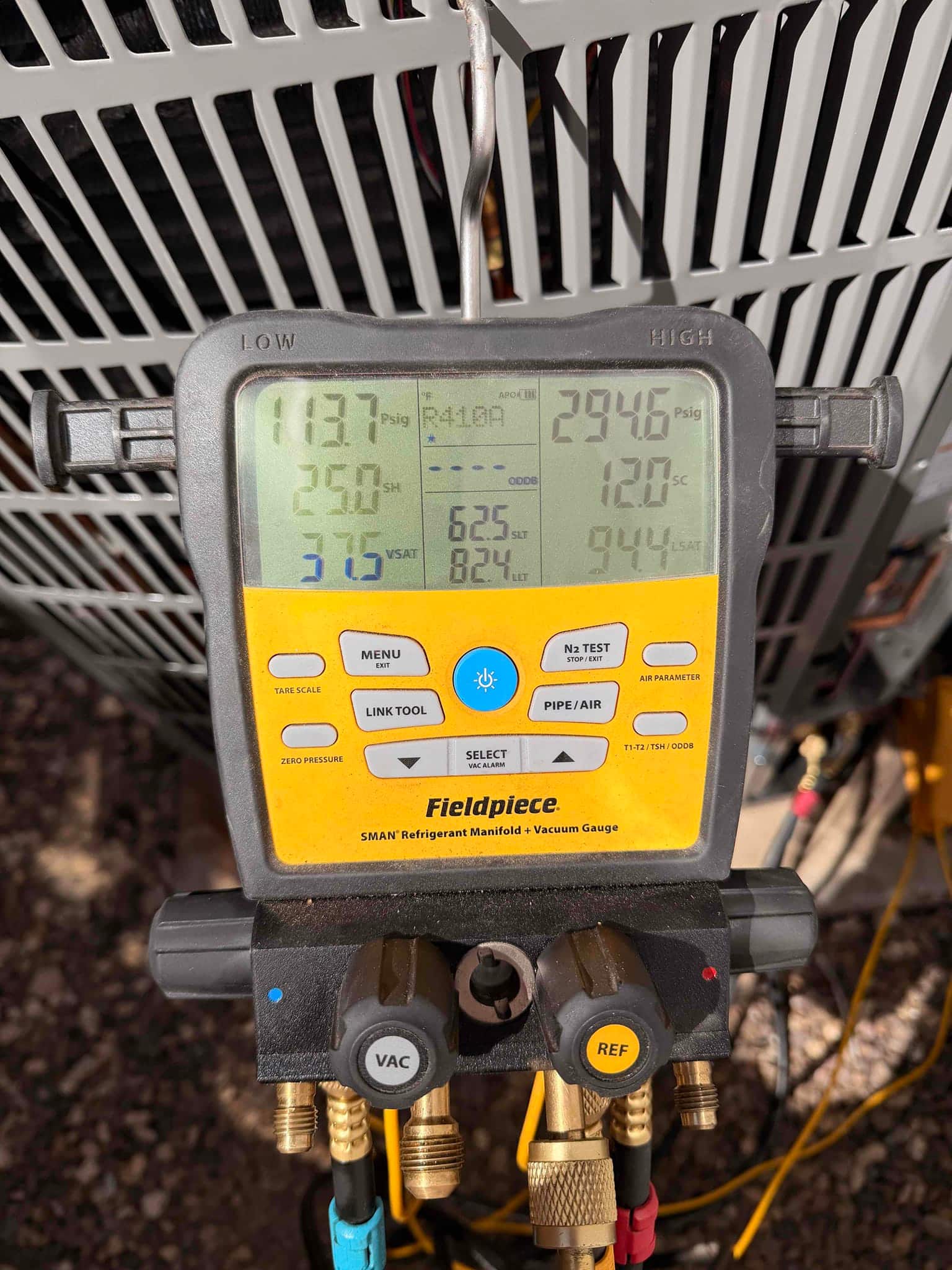 Digital manifold connected to the outdoor unit shows operating pressures and temperatures during system commissioning.