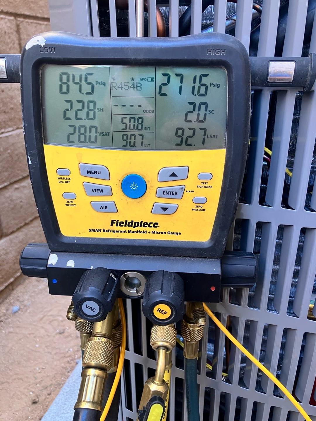 Digital manifold connected to the outdoor unit shows operating pressures and temperatures during system commissioning with refrigerant R-454B.