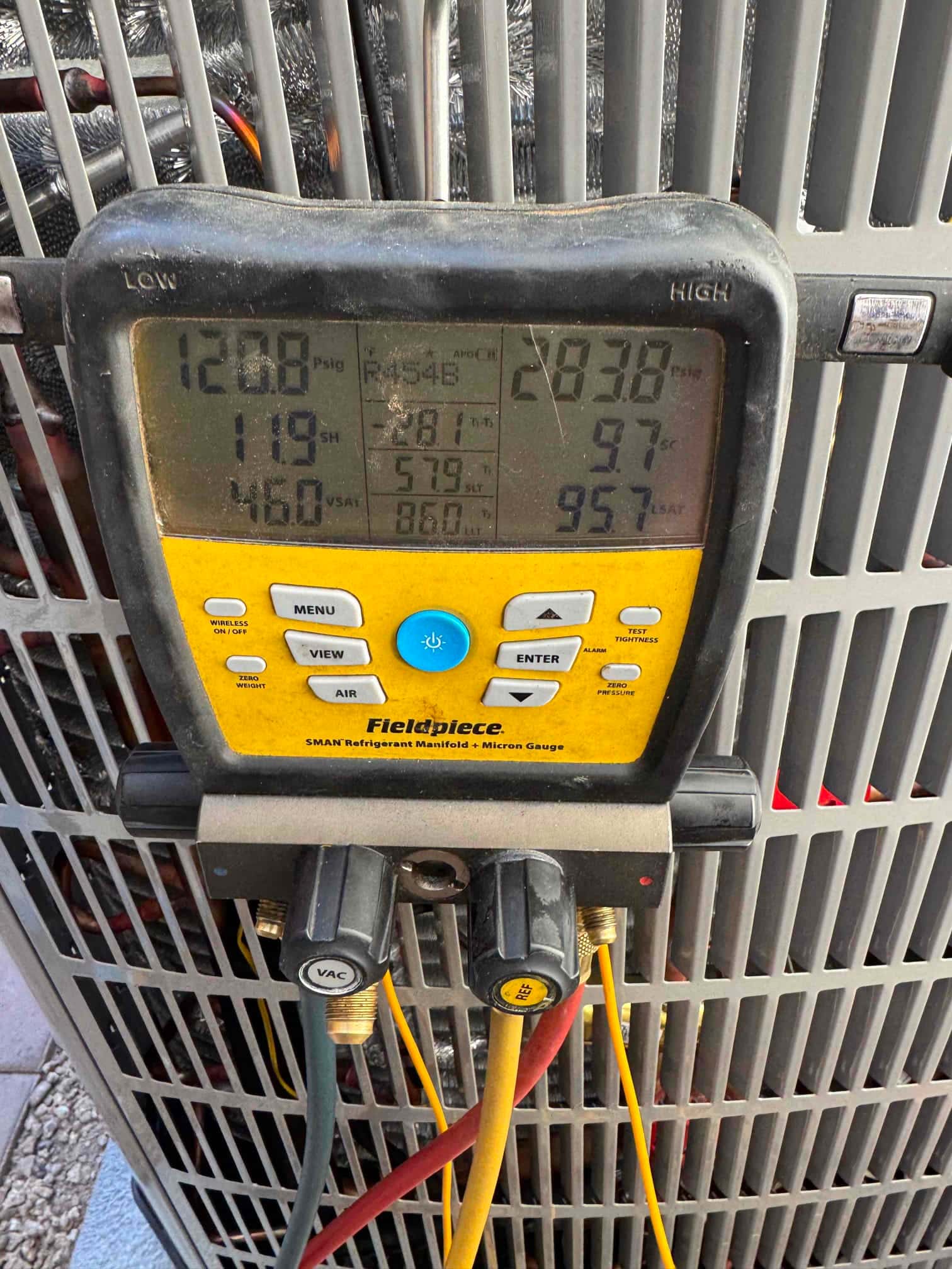 Digital manifold gauges connected to the outdoor unit show operating pressures and temperatures during system commissioning.